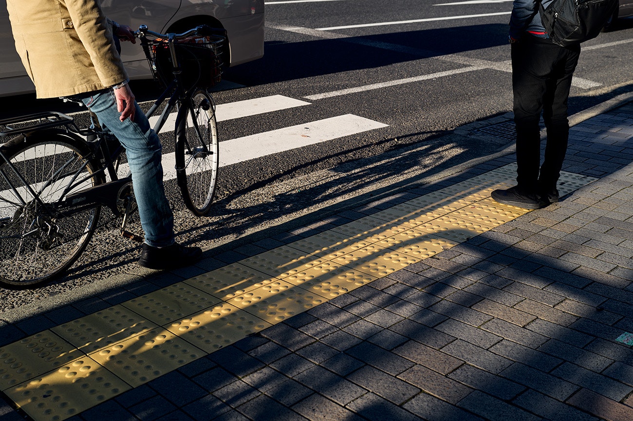 横断歩道の前で自転車を押す人と歩行者のいる街角
