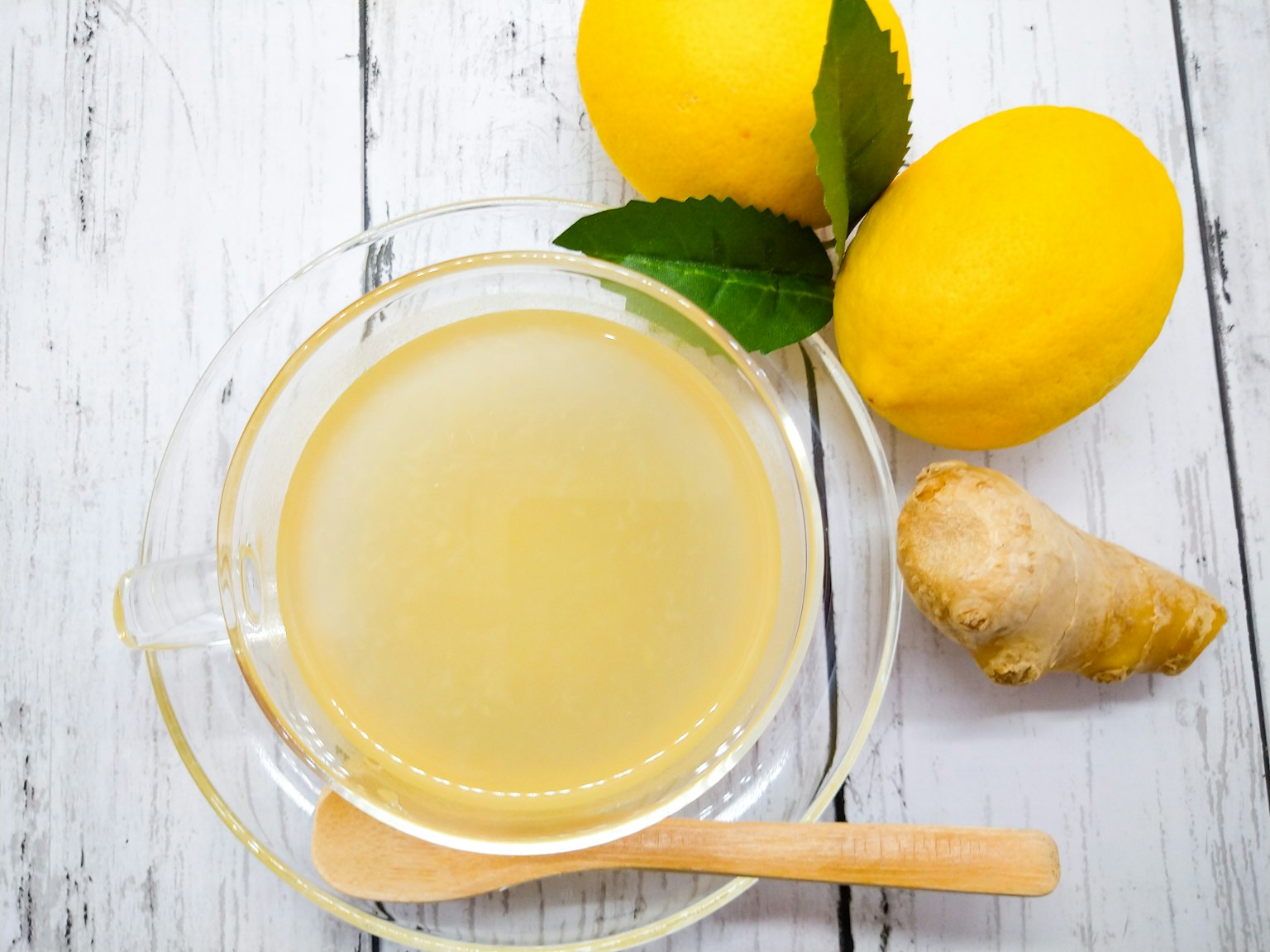 Une tasse de thé au gingembre et au citron avec des citrons frais et du gingembre sur une table en bois