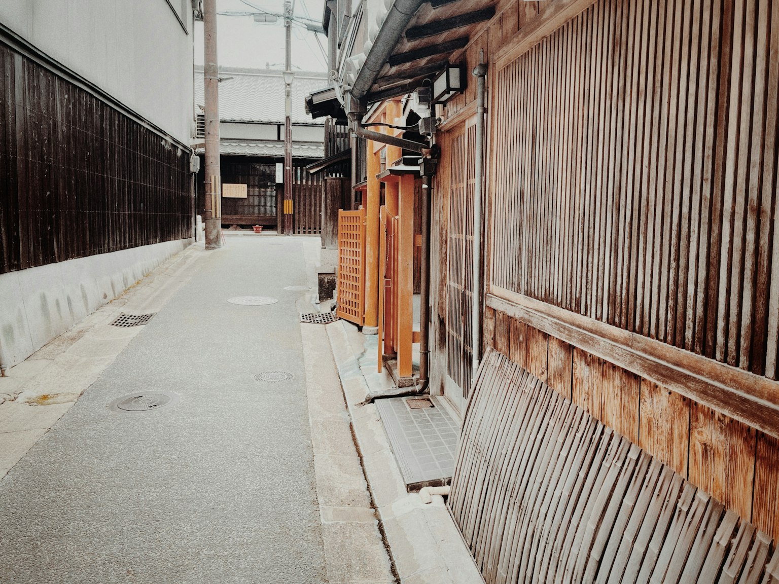 Narrow street lined with wooden walls and traditional buildings