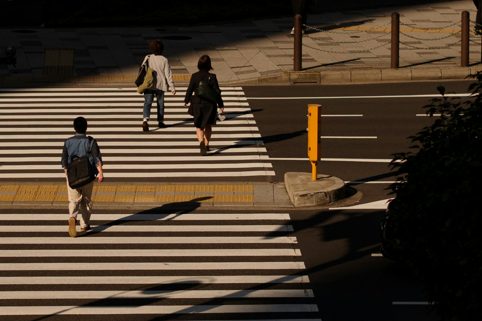 Des personnes traversant un passage piéton avec des ombres et de la lumière