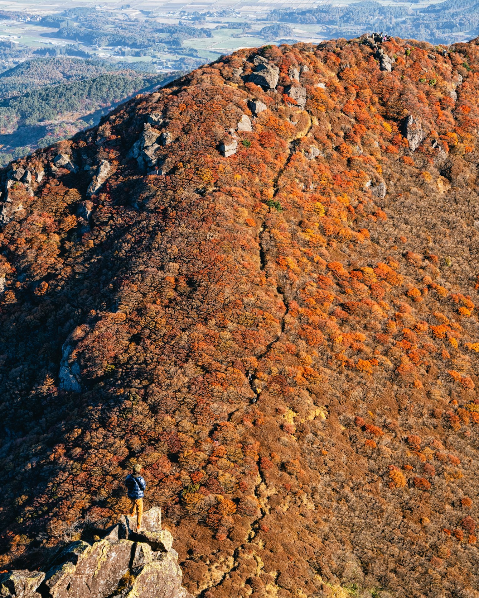 Senderista en la cima de una montaña con follaje de otoño