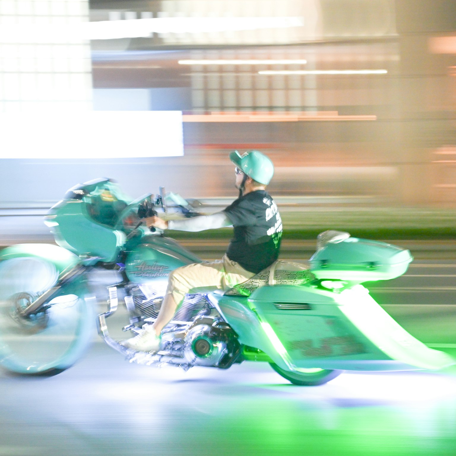 녹색 오토바이를 탄 라이더가 밤에 도시를 빠르게 질주하는 이미지로 움직임이 흐릿하게 표현됨