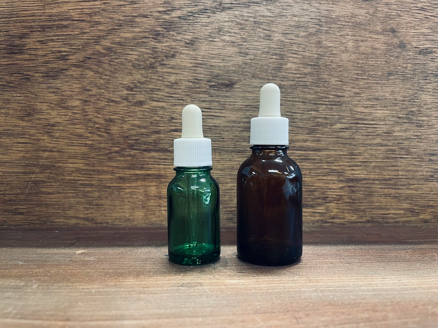 绿色和棕色玻璃瓶放置在木质背景上