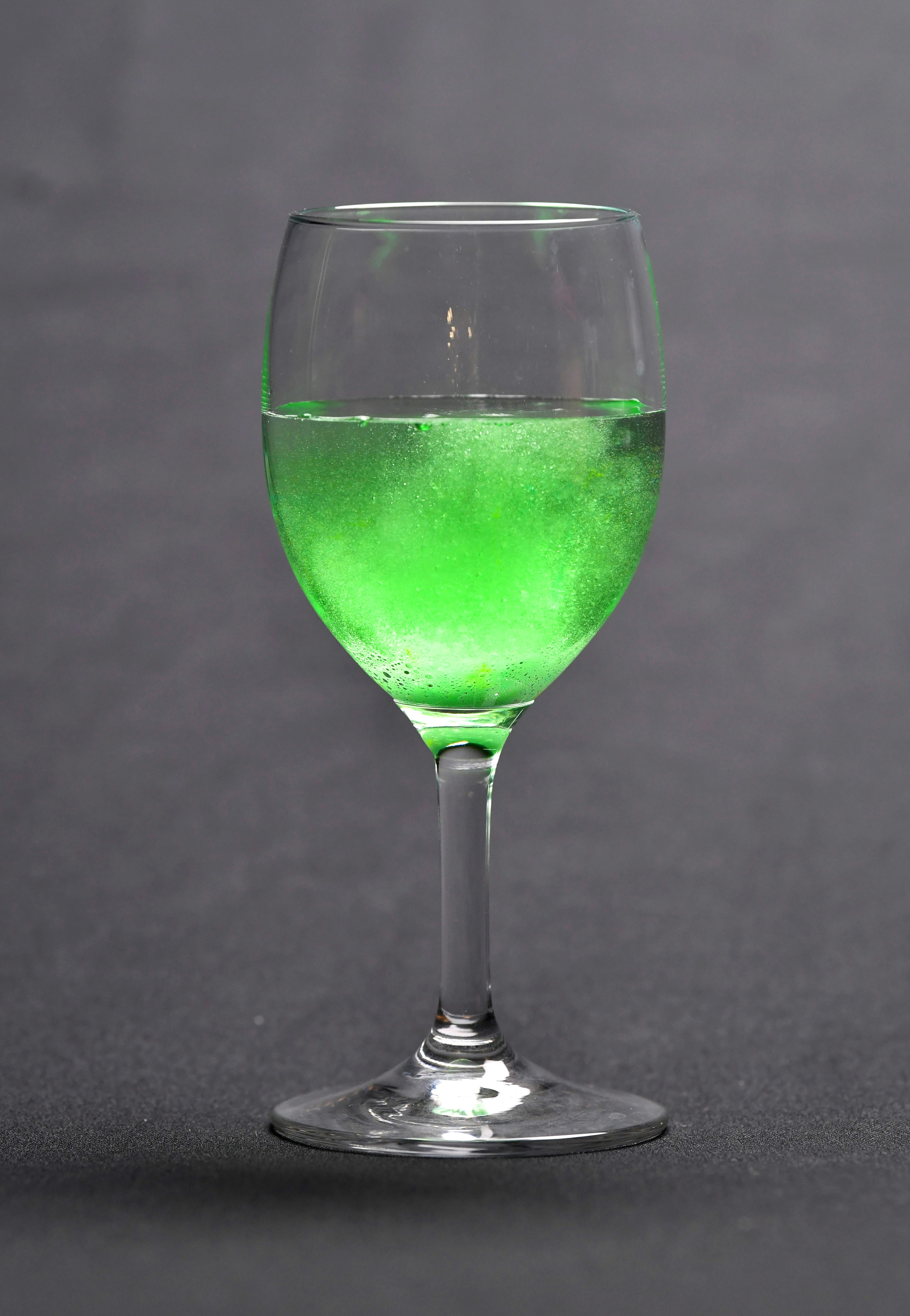 緑色の液体が入ったワイングラスの静物画像