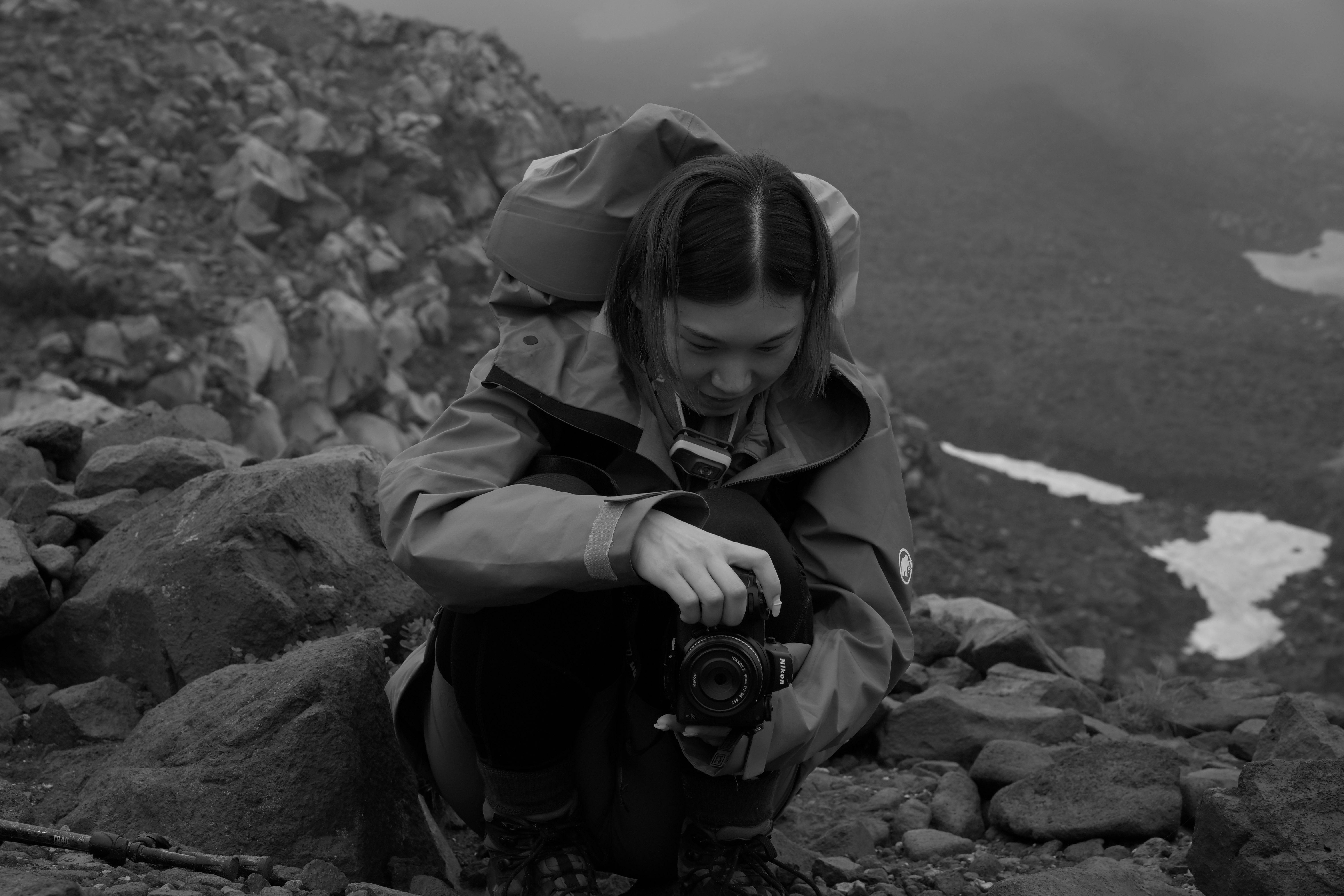 Escursionista seduta su terreno roccioso con una fotocamera