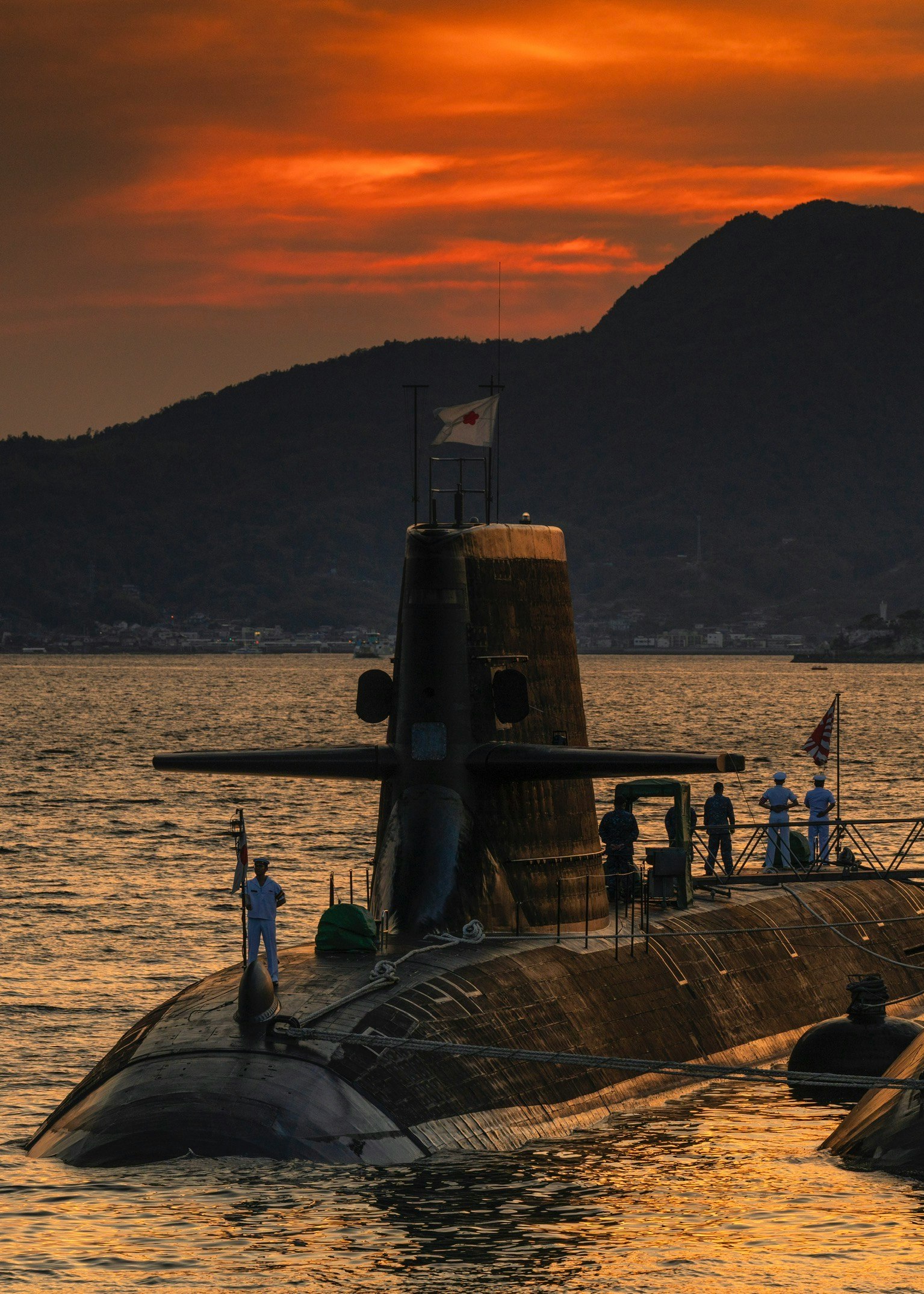夕焼けの海上で浮かぶ潜水艦の甲板と乗組員