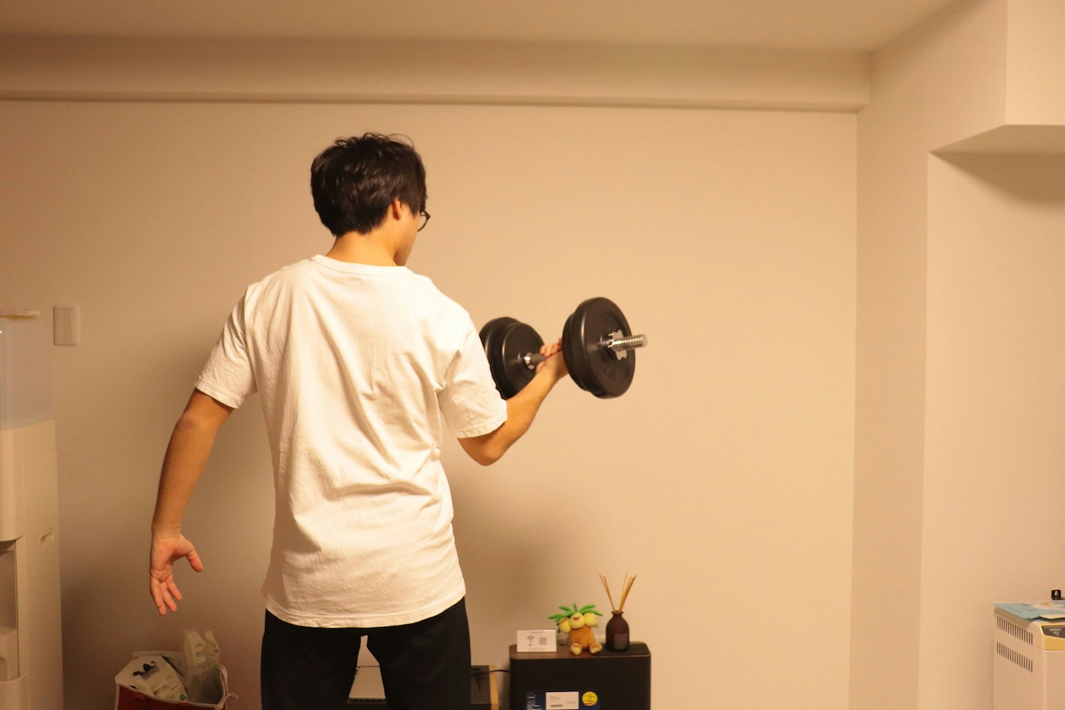 Mann, der mit Hanteln trainiert, mit dem Rücken zur Wand