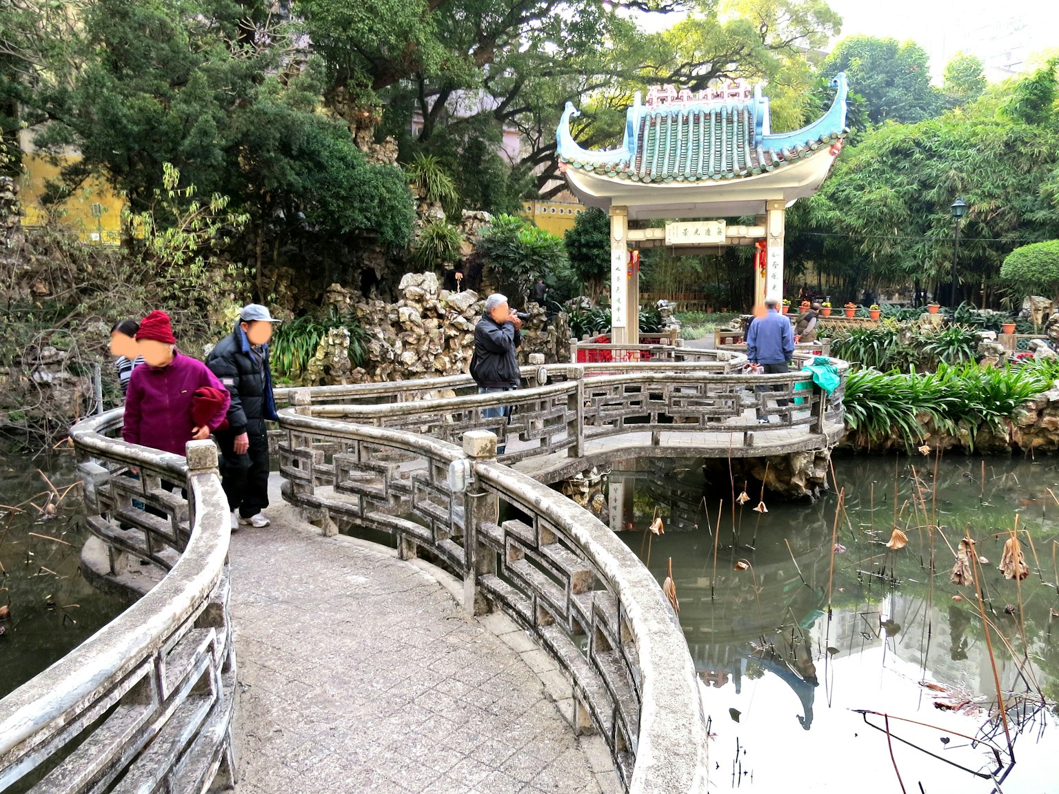 Persone che camminano su un ponte da giardino con un padiglione in stile cinese