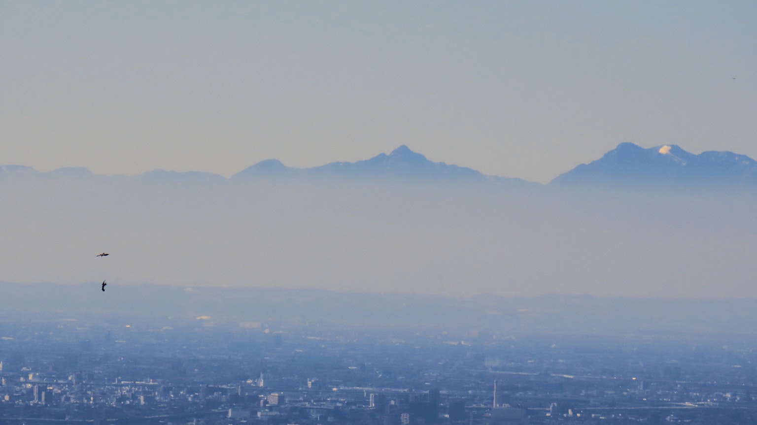 View of blue mountains shrouded in mist with a city landscape