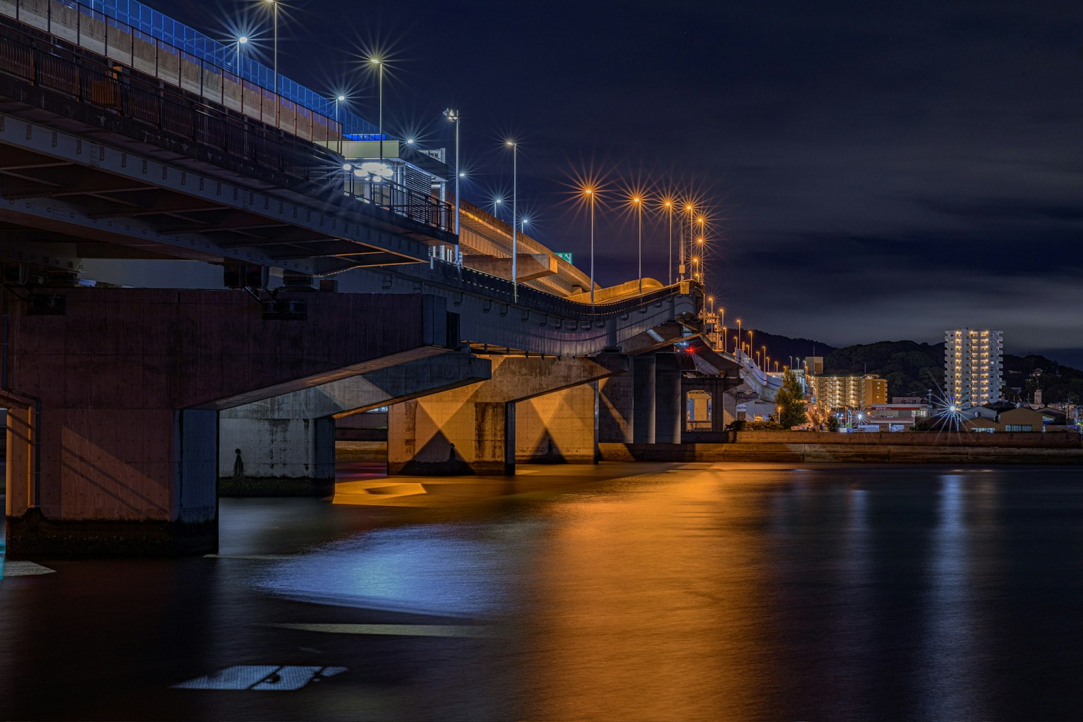 Vista nocturna de un puente con reflejos en el agua