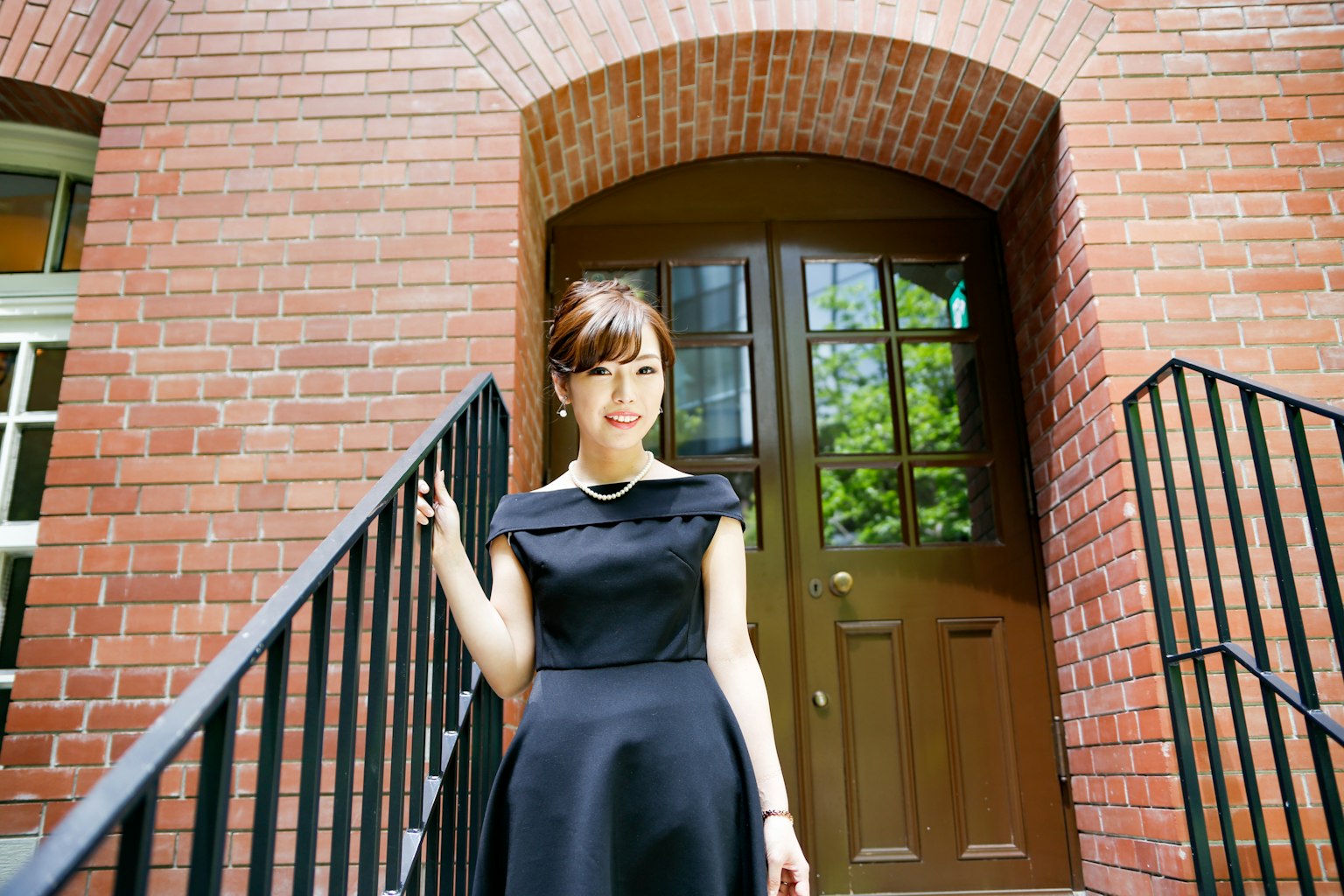 一位穿着黑色裙子的女性站在砖砌建筑前