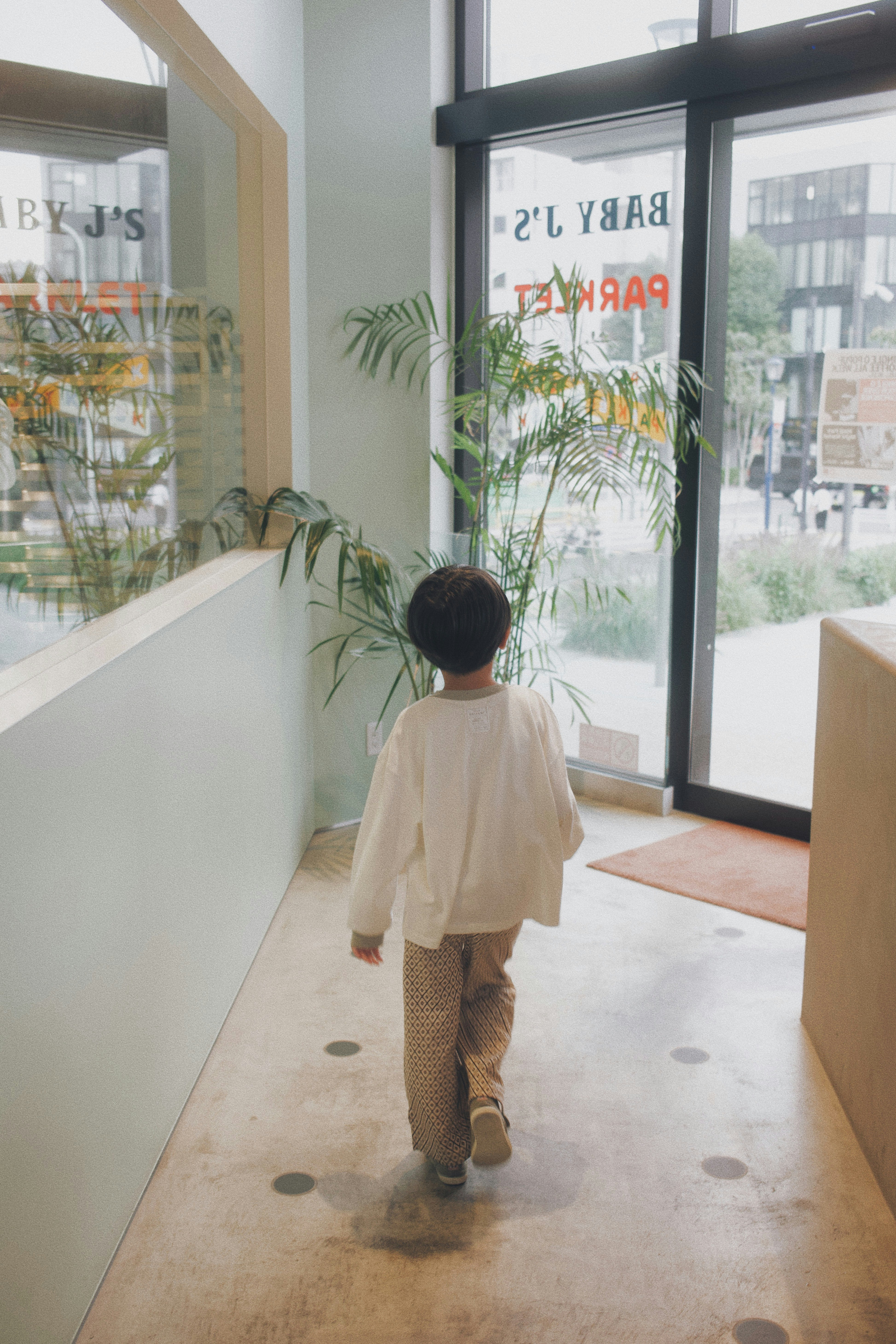 child walking along an indoor corridor with glass windows