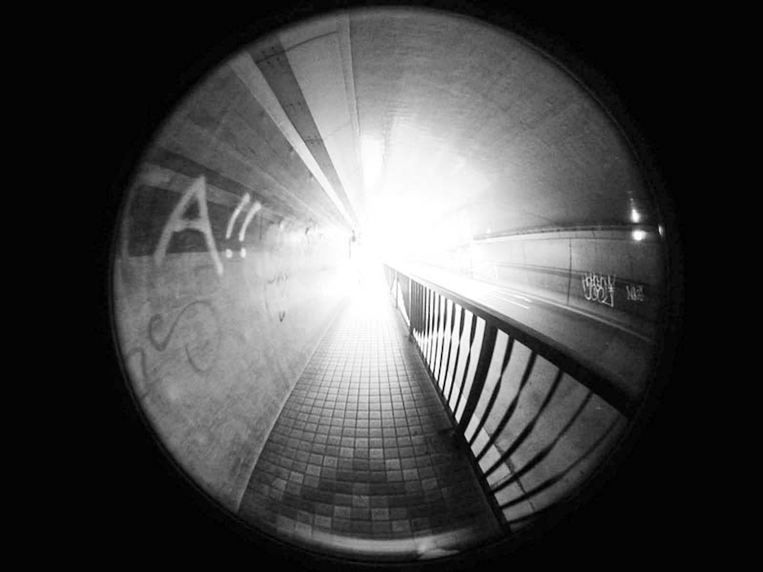 Intérieur d'un tunnel avec une lumière vive qui brille des lignes distinctives et une rampe en fer