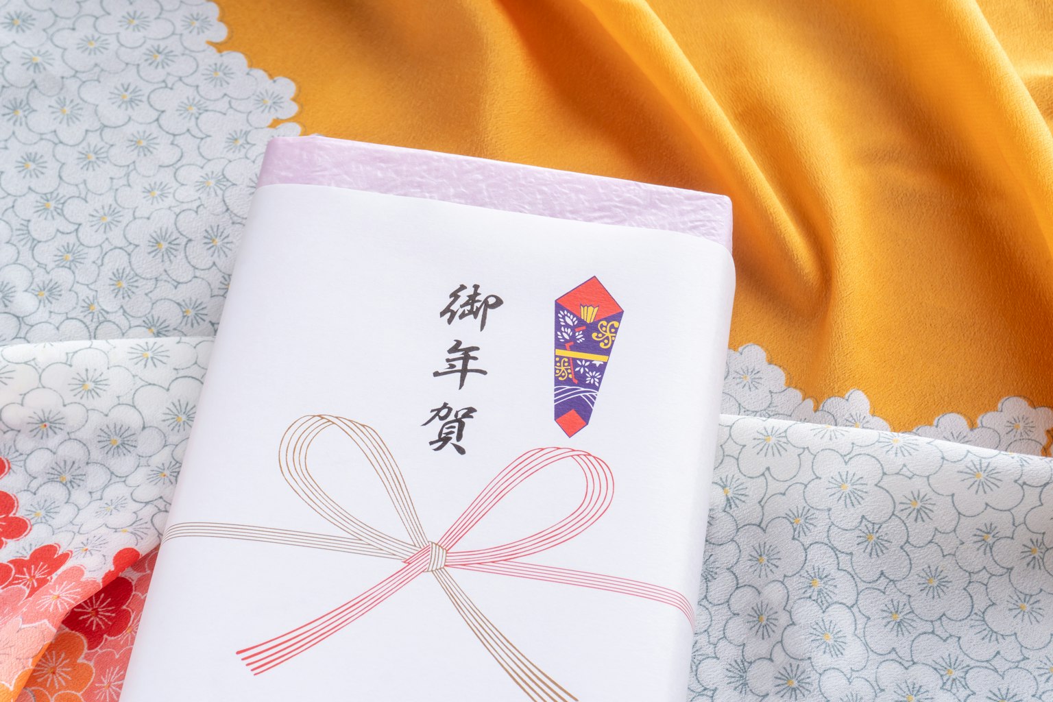 Une enveloppe blanche nouée avec un ruban rose posée sur un tissu coloré