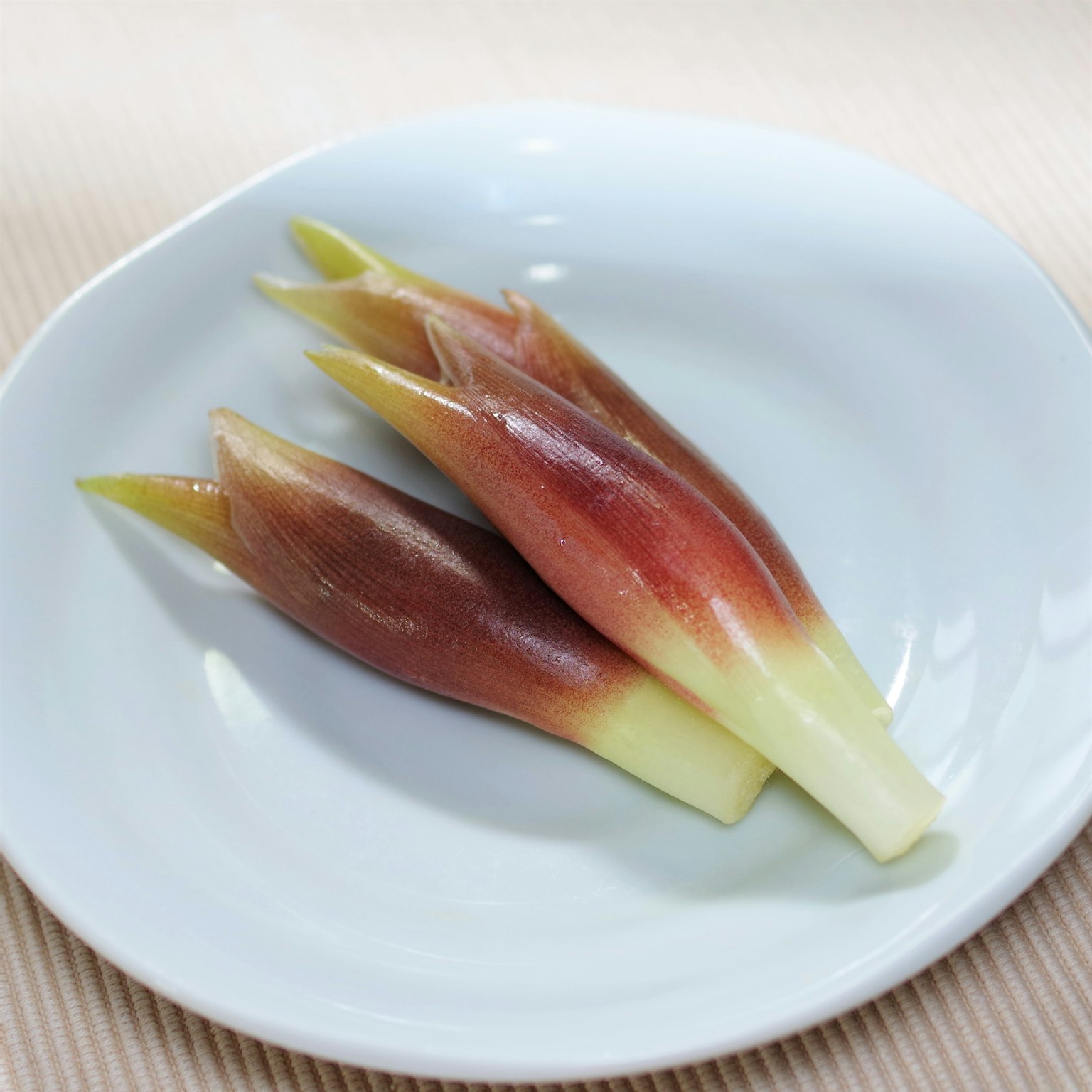 Boccioli di verdura fresca disposti su un piatto bianco