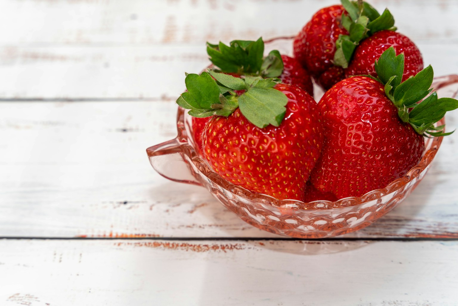 A glass bowl filled with fresh red strawberries