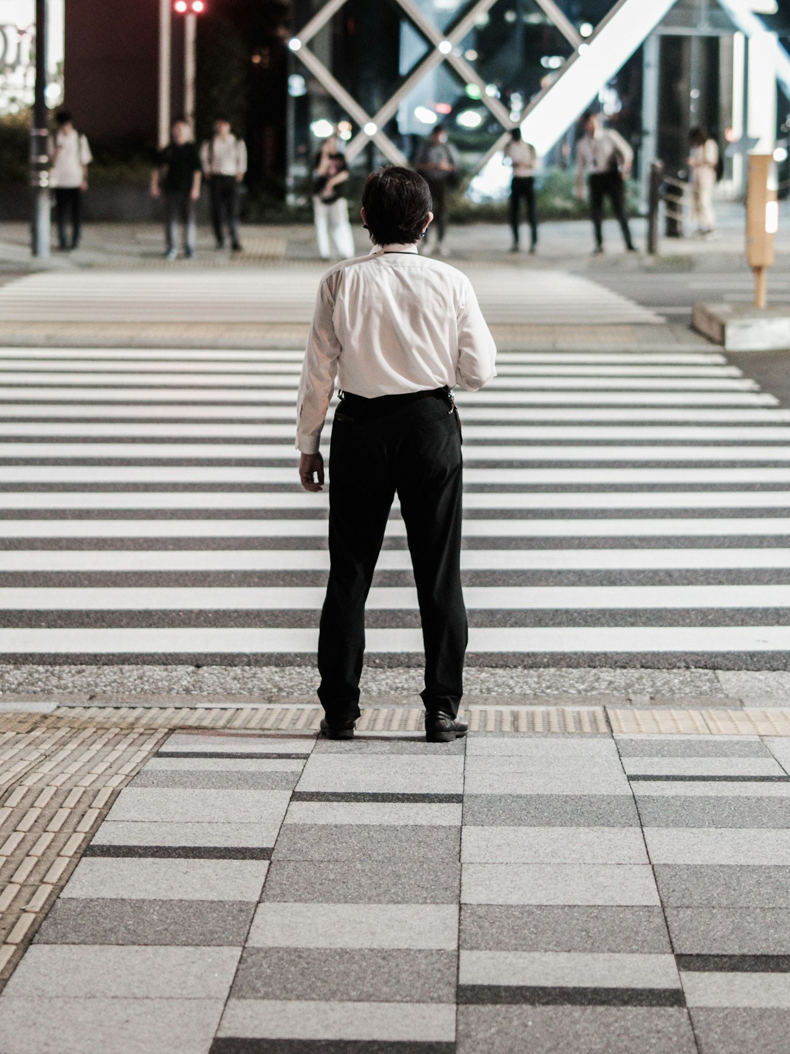 Un homme en chemise blanche se tenant à un passage piéton