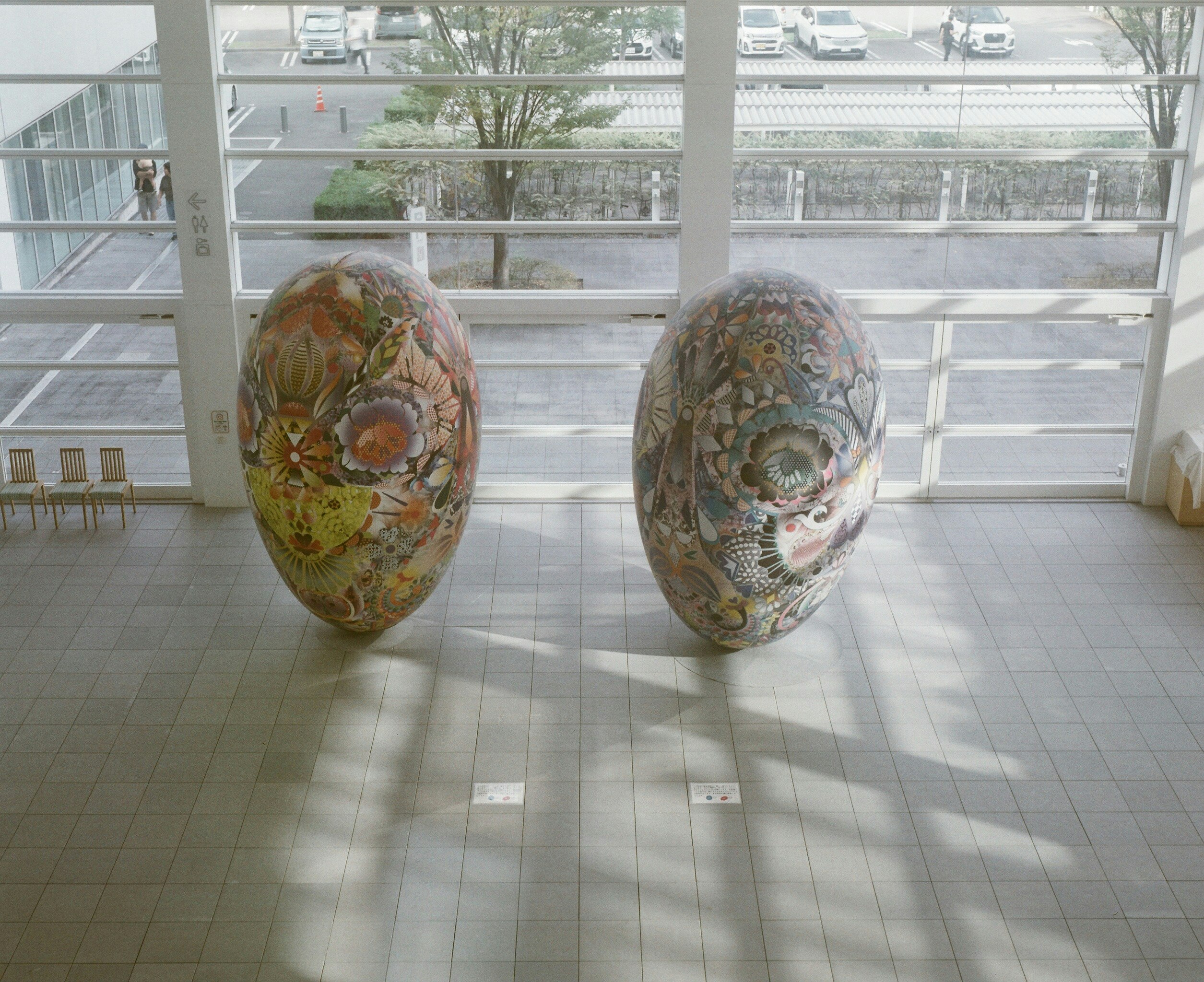 ガラス越しの展示室で並ぶ装飾的な卵形オブジェ