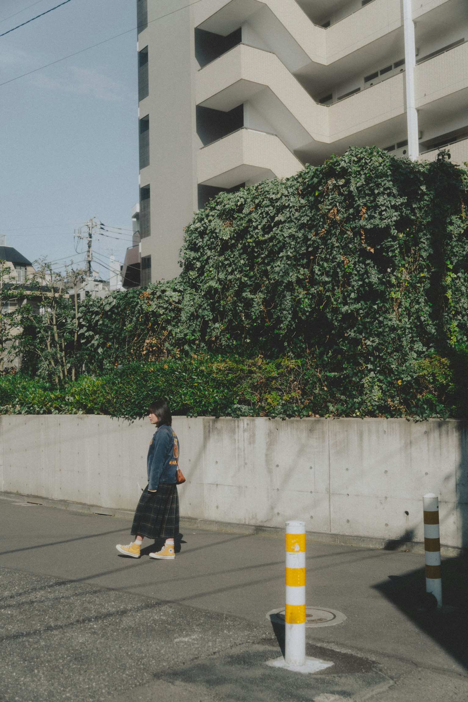 女性走在郁郁葱葱的墙前和现代建筑旁