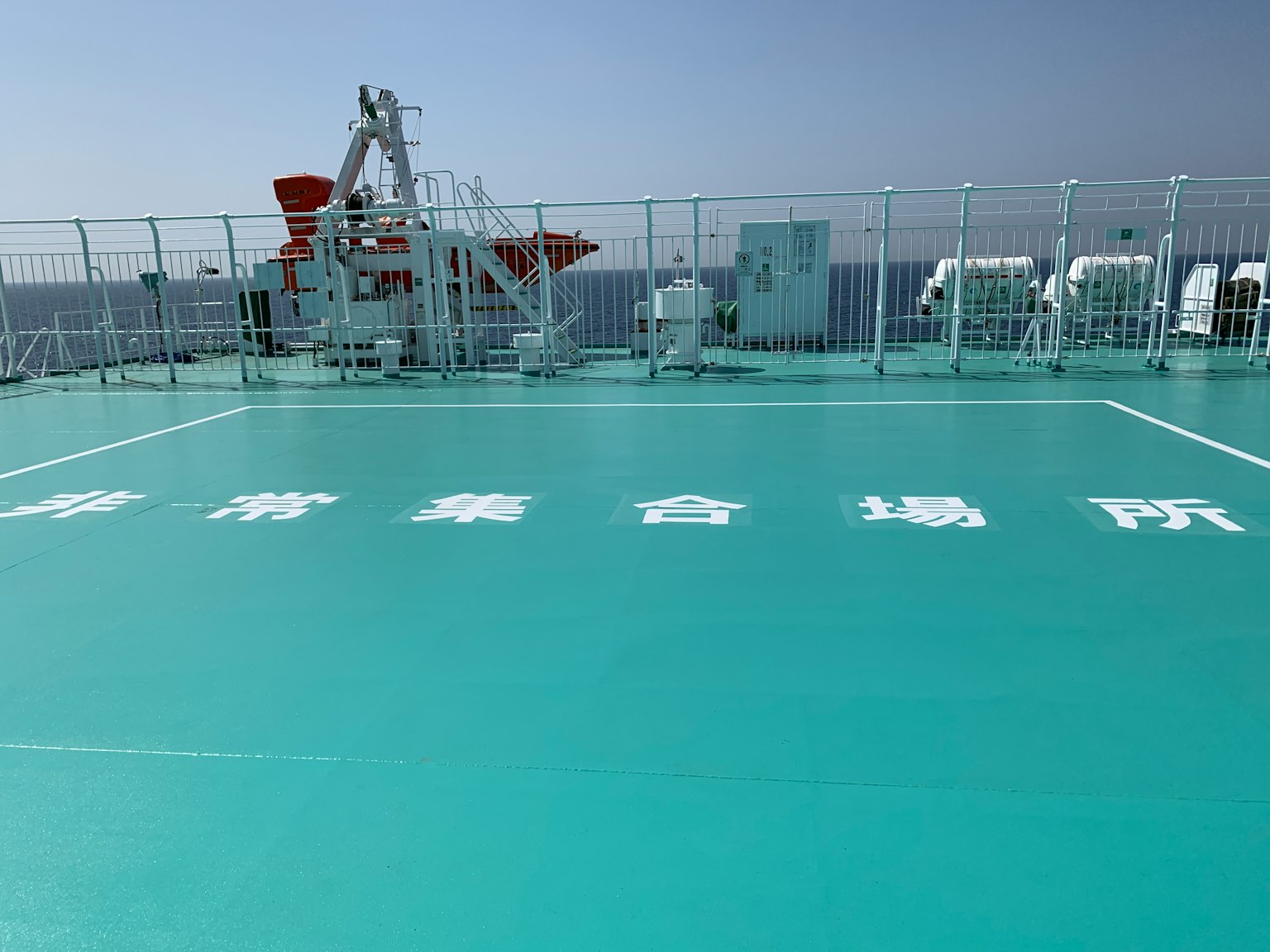 Immagine di un ponte verde su una nave con testo bianco visibile attrezzatura navale sullo sfondo