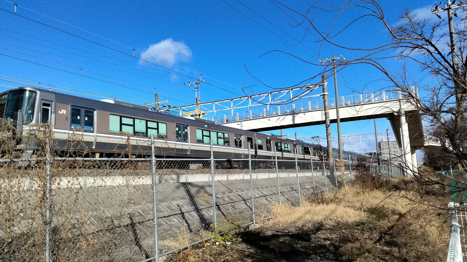Train traveling under a blue sky with an overpass