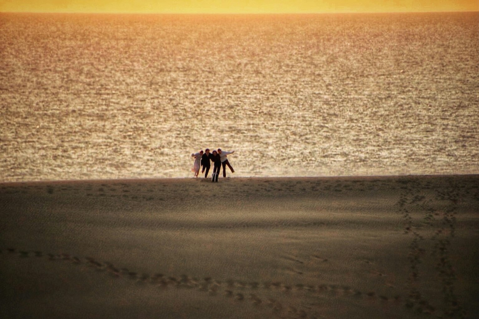 Silhouette di persone che si radunano sulla spiaggia con il tramonto sullo sfondo