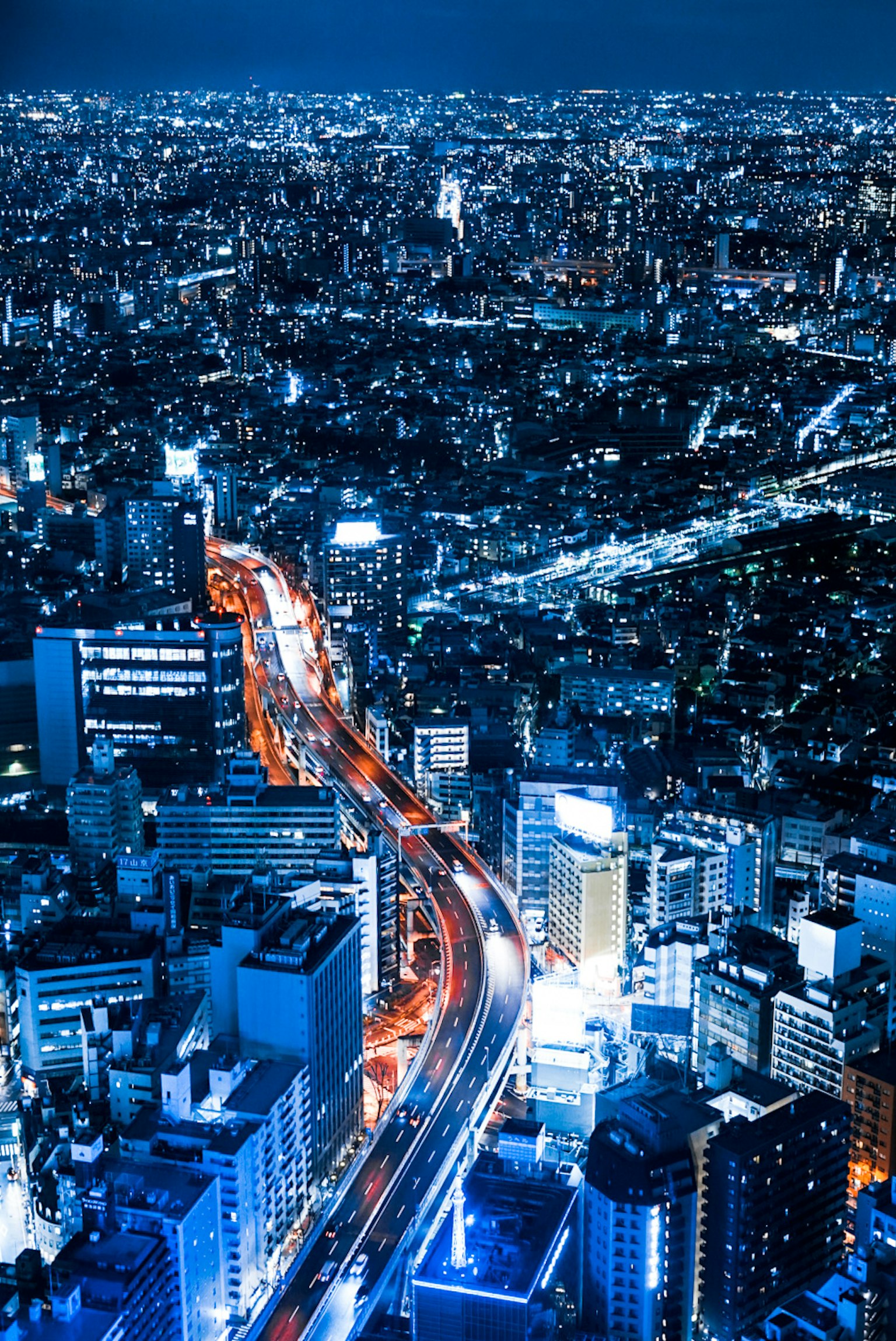 Pemandangan malam Tokyo dengan gedung pencakar langit dan jalan yang diterangi
