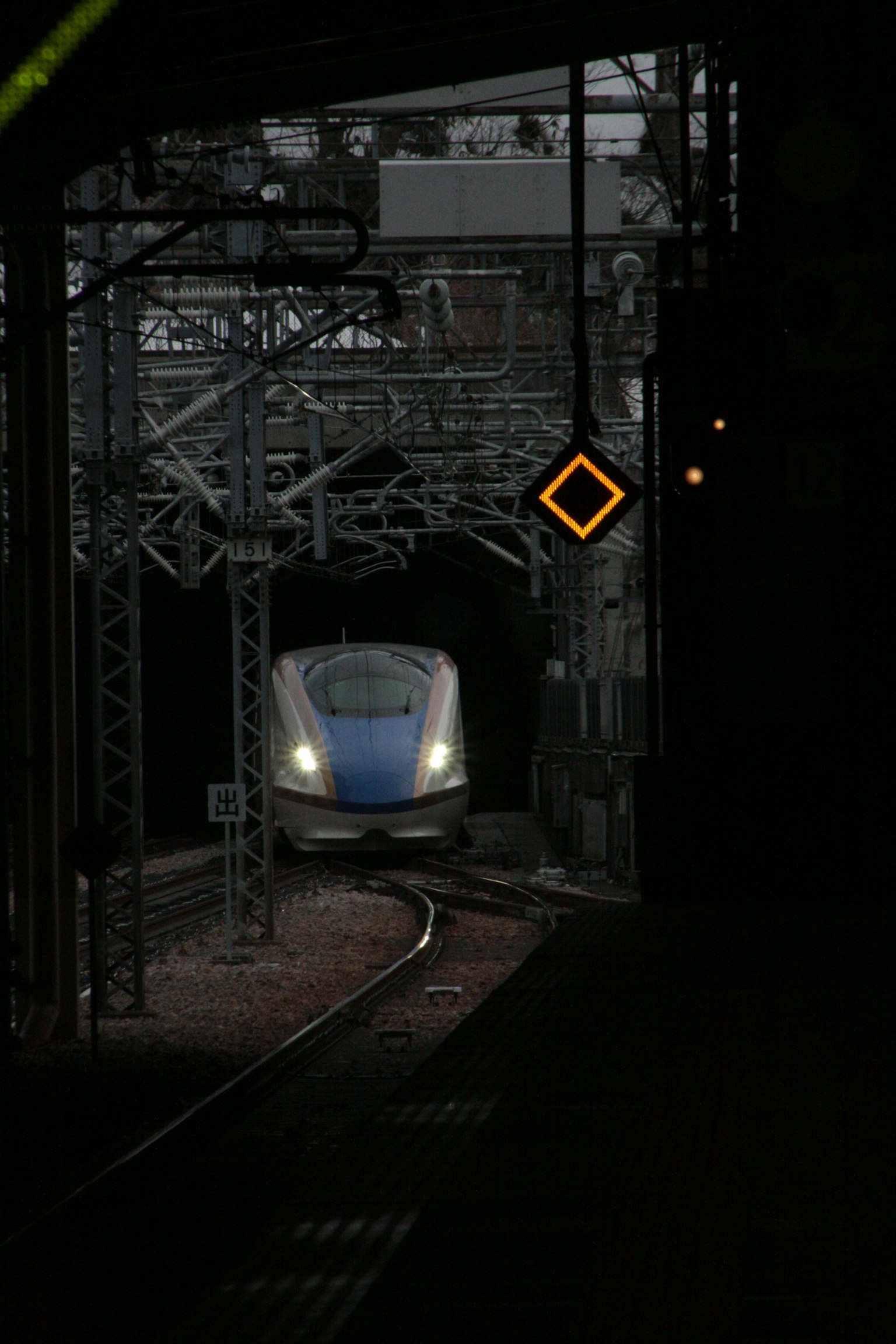 Shinkansen mendekati tikungan di stasiun yang redup