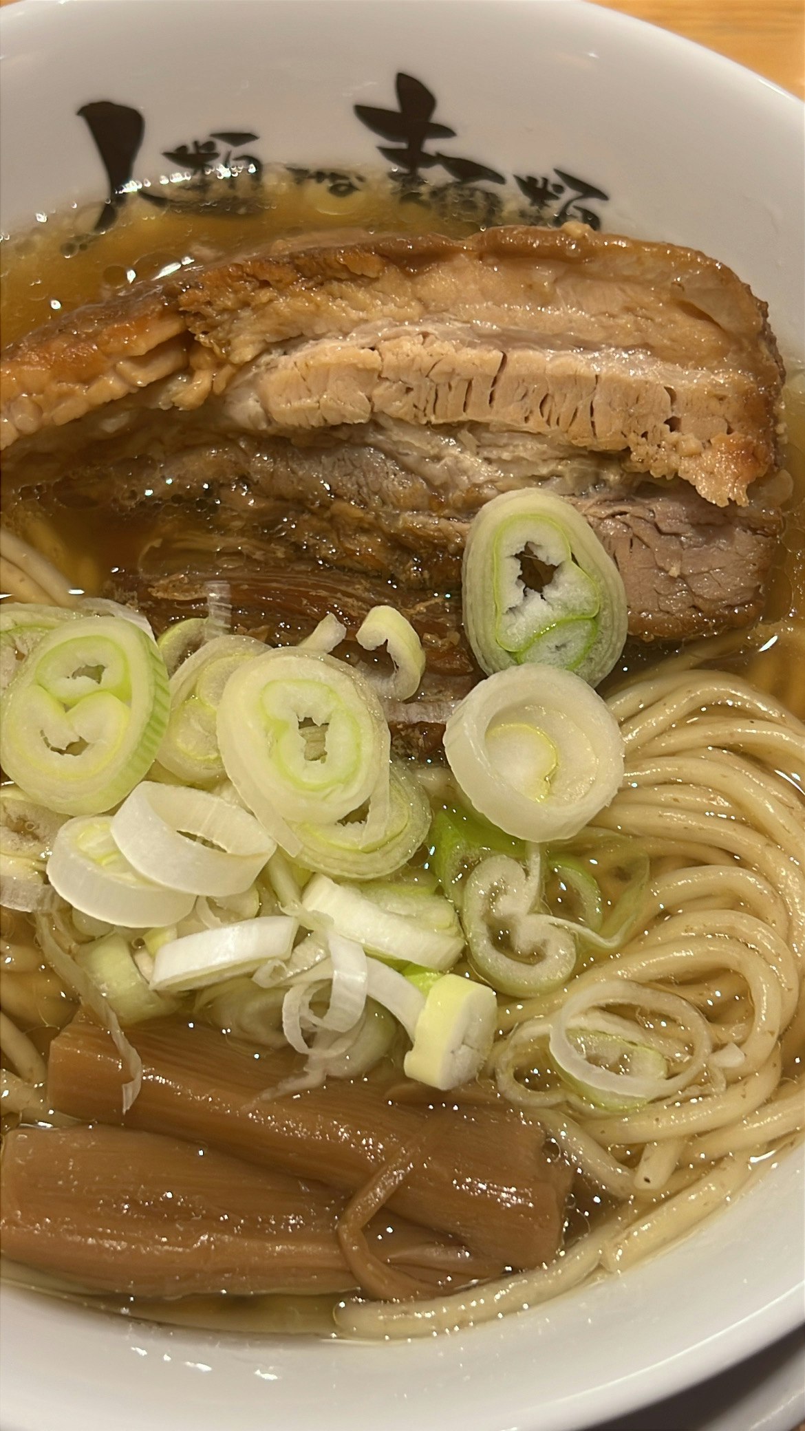 bowl of ramen with sliced green onions and pork