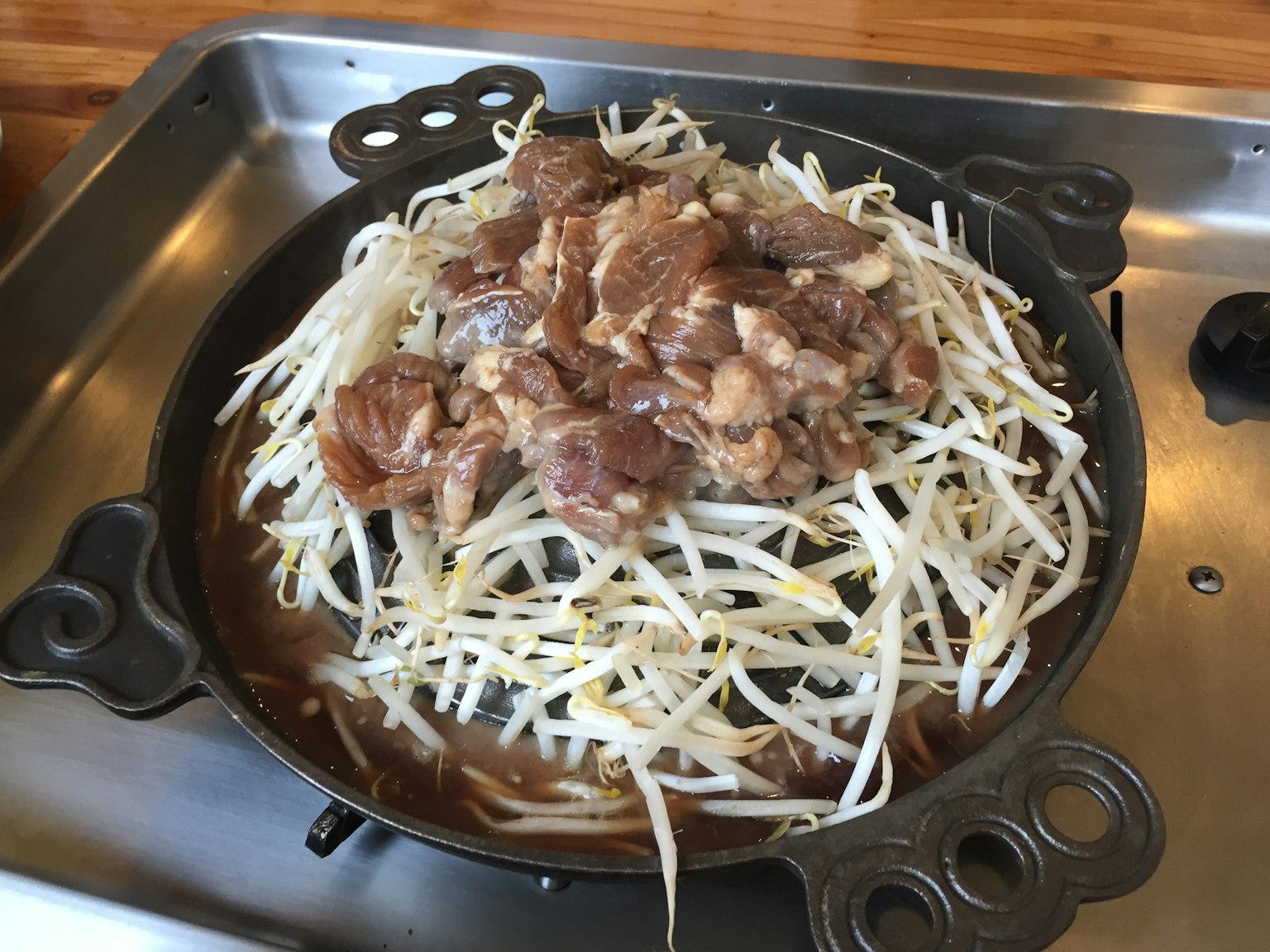 一盤烤肉，上面放著豆芽