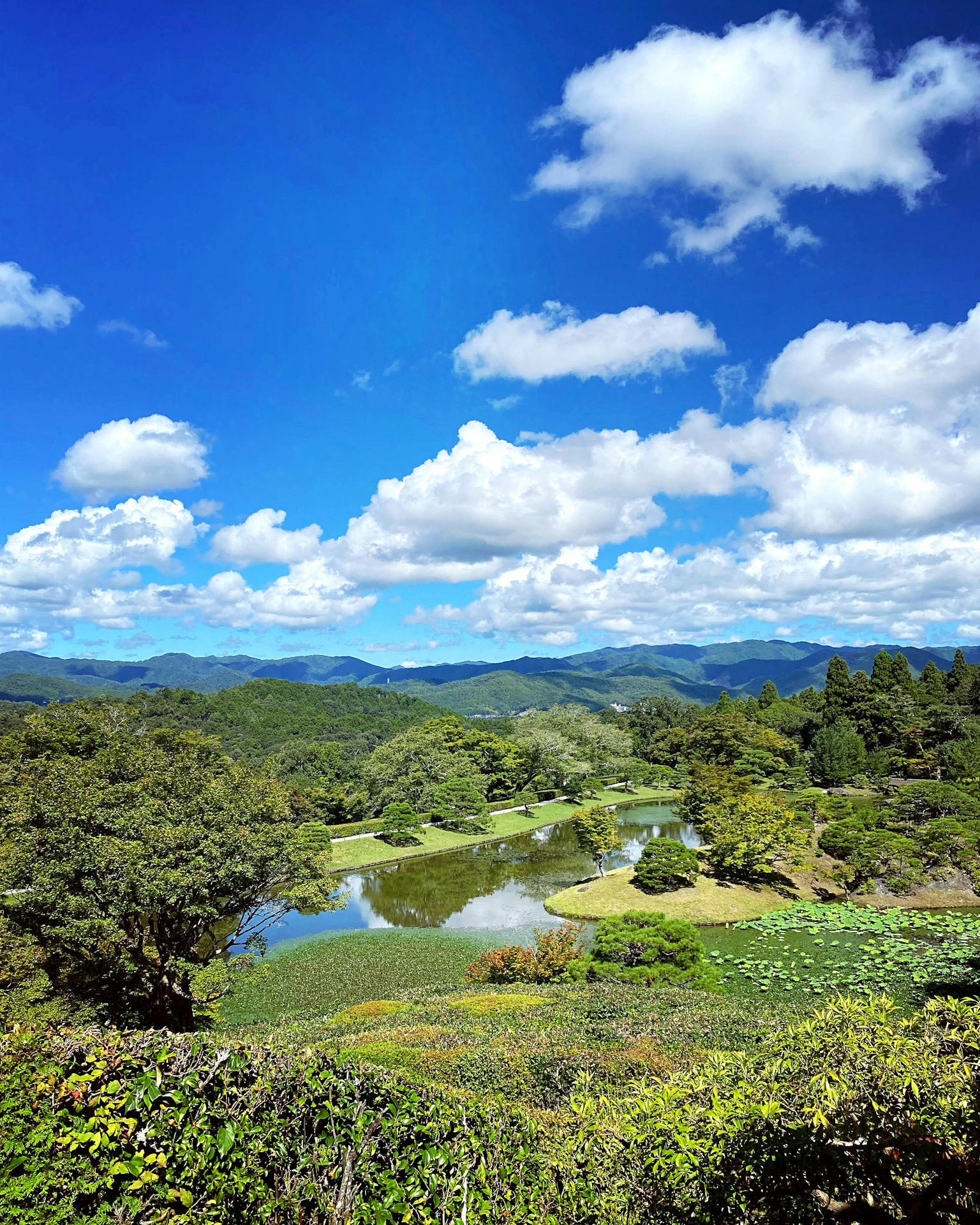 Vue panoramique avec ciel bleu et nuages blancs collines verdoyantes et lac calme