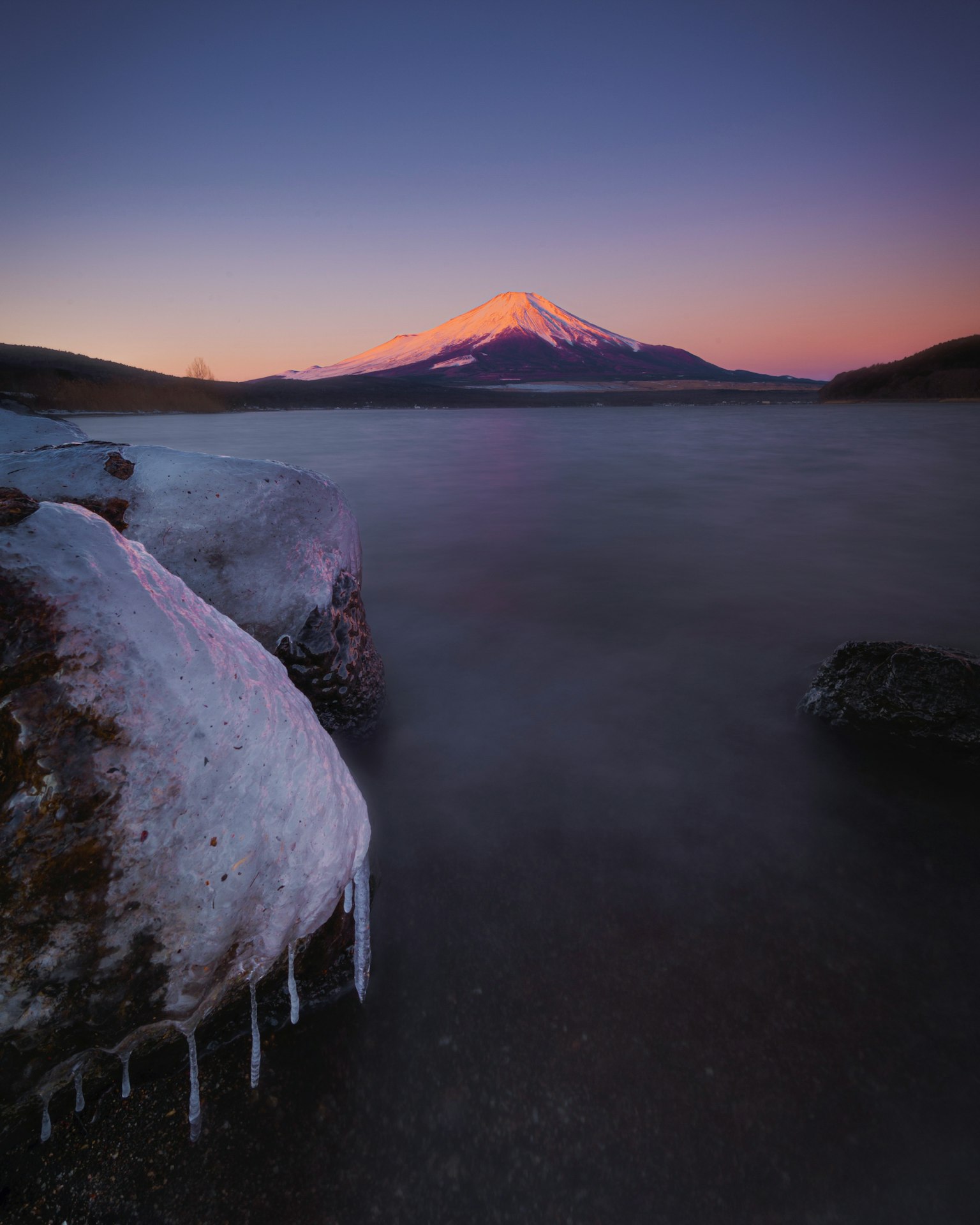 Snow-covered rock and frozen lake foreground with beautiful mountain landscape