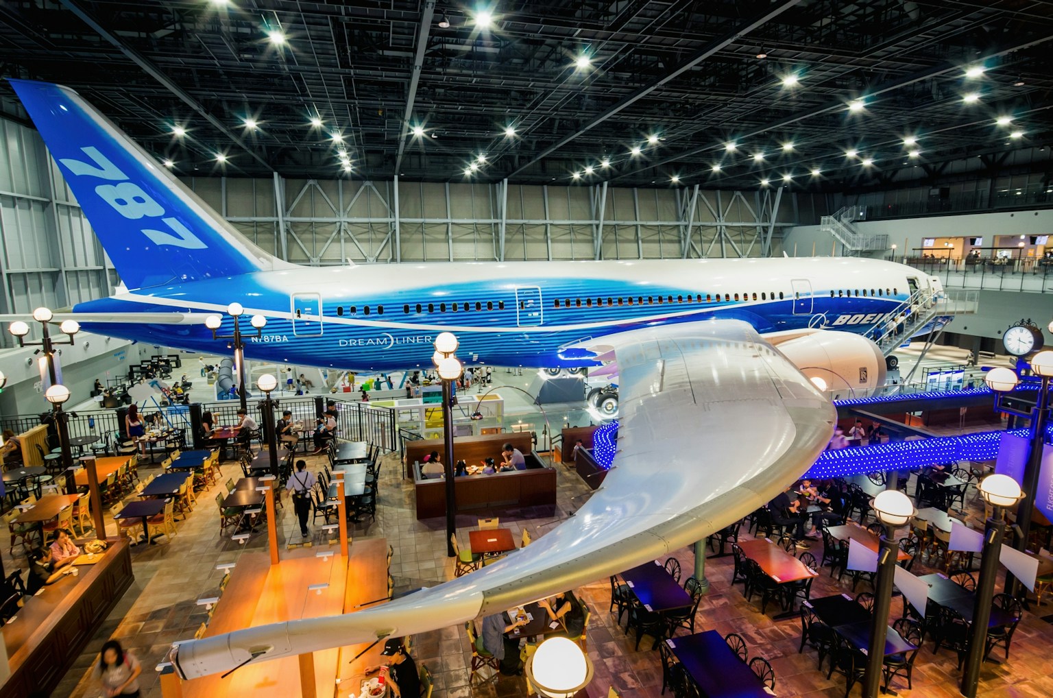 Ein Boeing 787 Flugzeug in einem großzügigen Bereich mit einem belebten Essbereich ausgestellt
