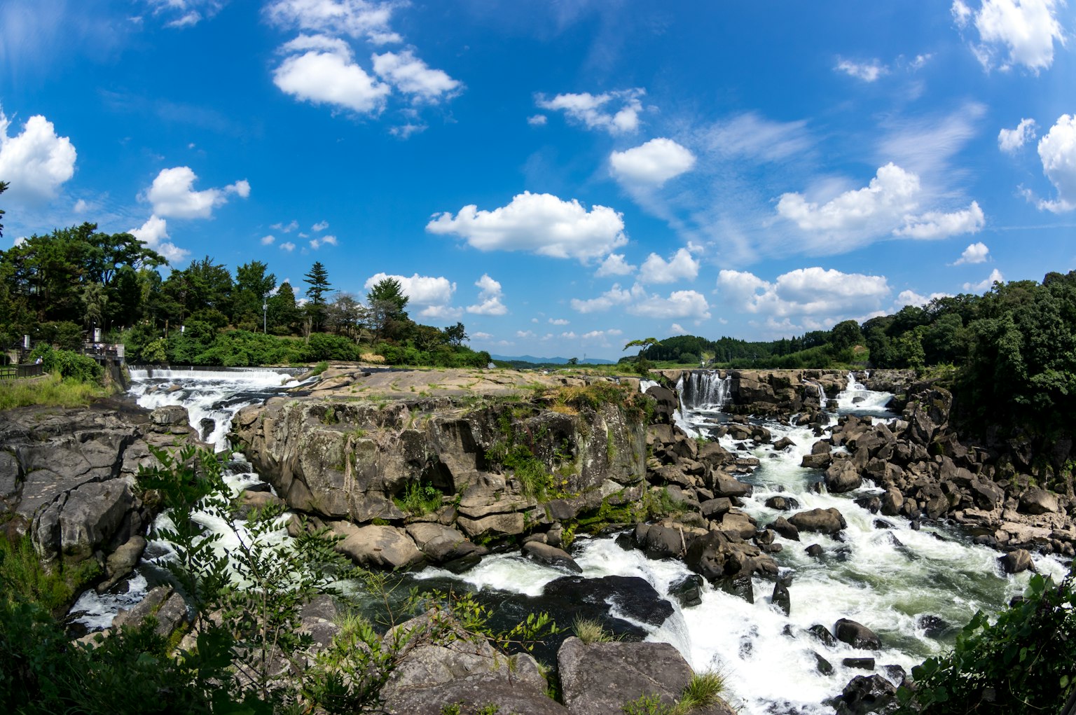 Paesaggio di cascata panoramico con cielo blu vegetazione lussureggiante e terreno roccioso