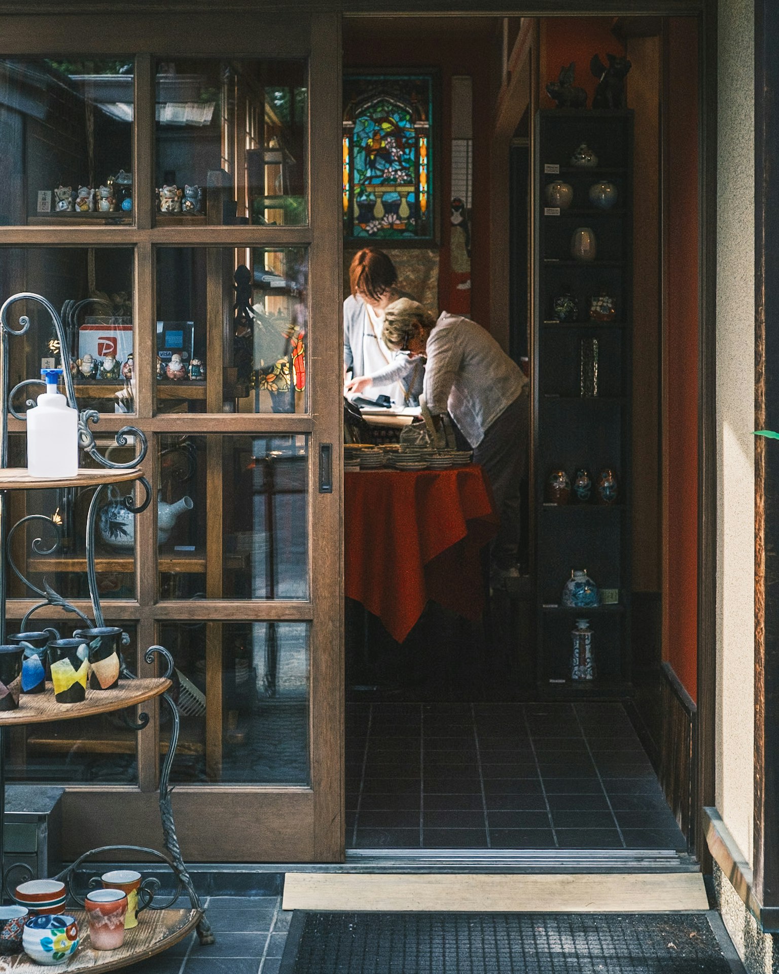 Entrada de una tienda vintage con dos personas en una mesa y cerámica colorida