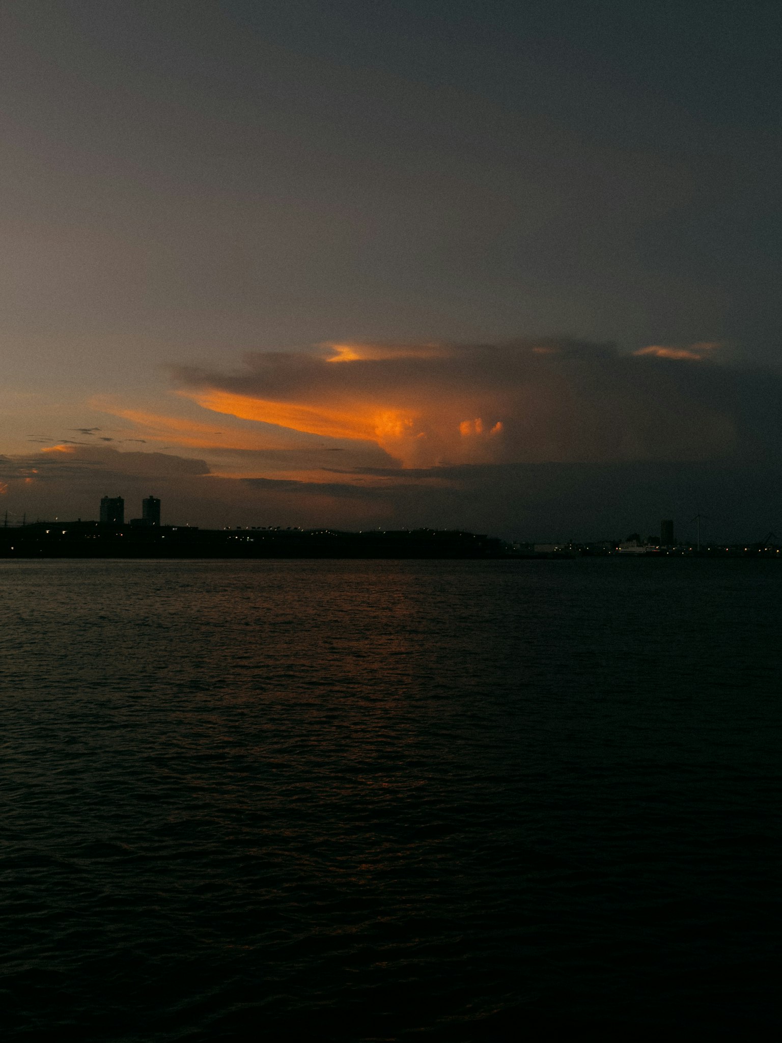 Orangefarbener Sonnenuntergang leuchtet zwischen Wolken über dem Ozean in der Dämmerung