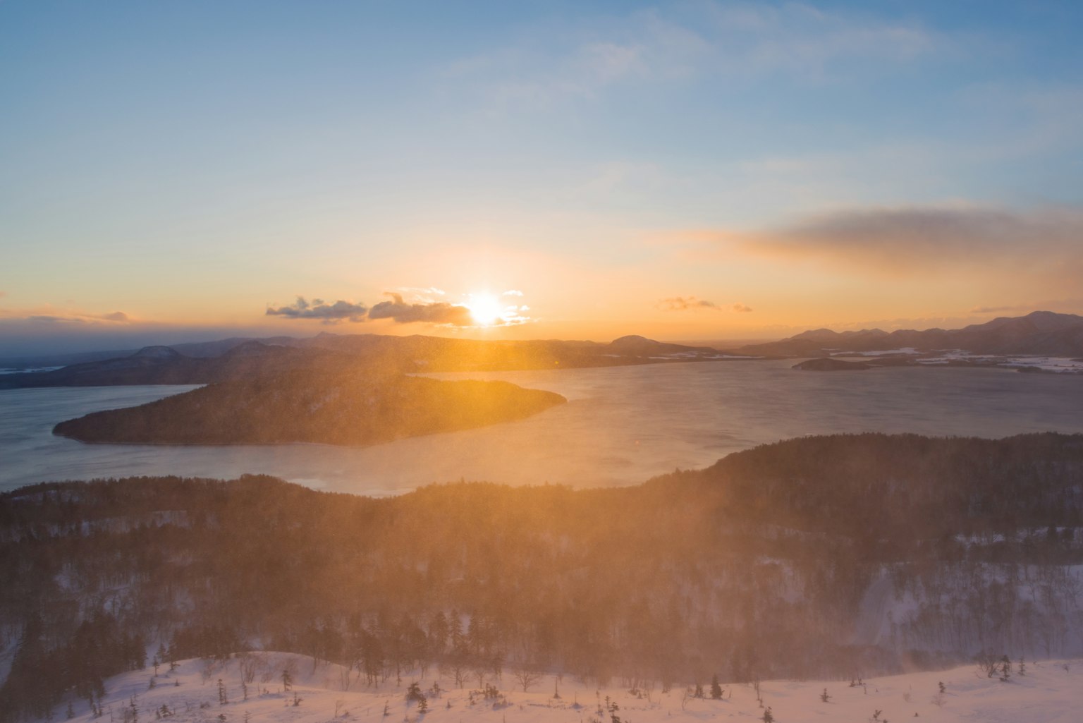 Wunderschöner Sonnenuntergang über schneebedeckten Bergen und See