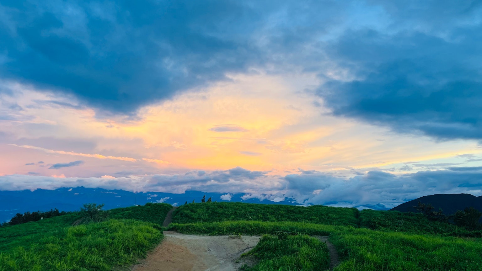 美麗的夕陽天空與綠色山丘