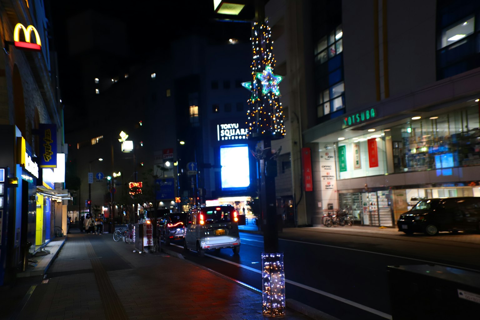 Calle de la ciudad iluminada por la noche con letrero de McDonald's