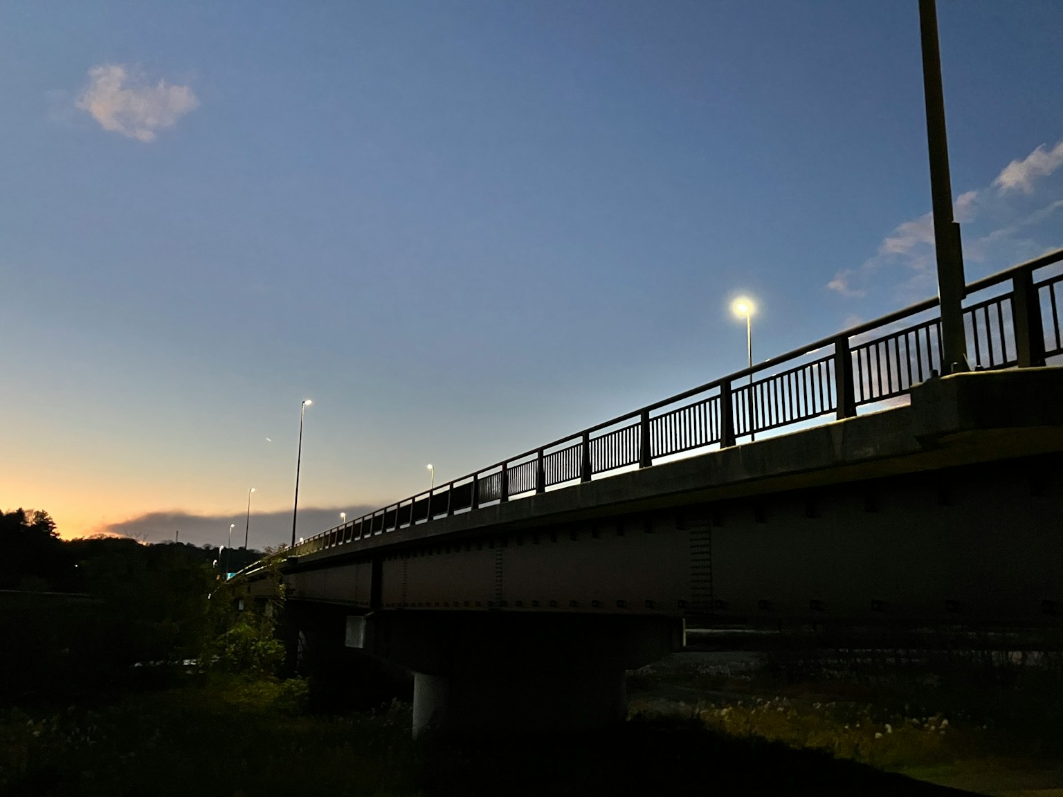 Silhouette of a bridge during twilight with streetlights