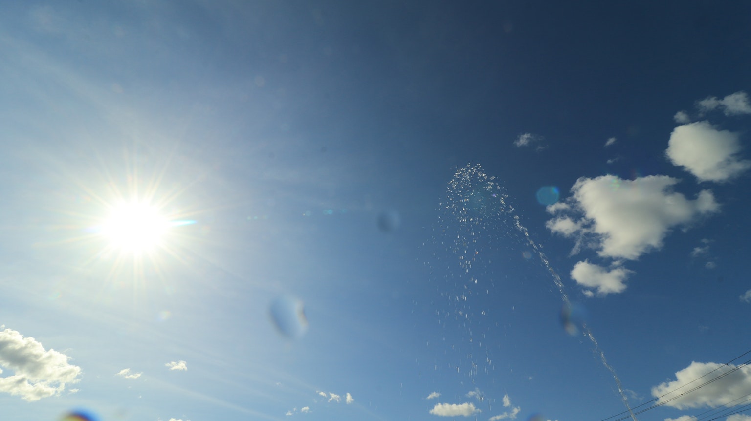 Langit biru dengan awan putih dan matahari Percikan air meluncur ke atas