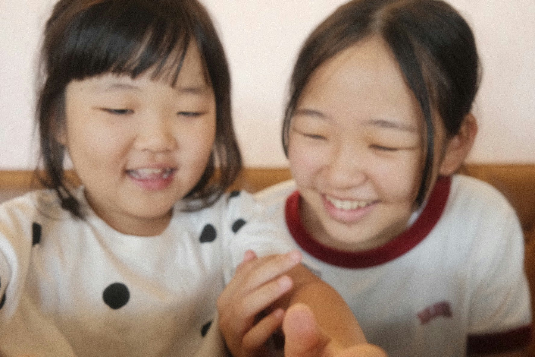姉妹が寄り添って笑顔で手をつないでいる
