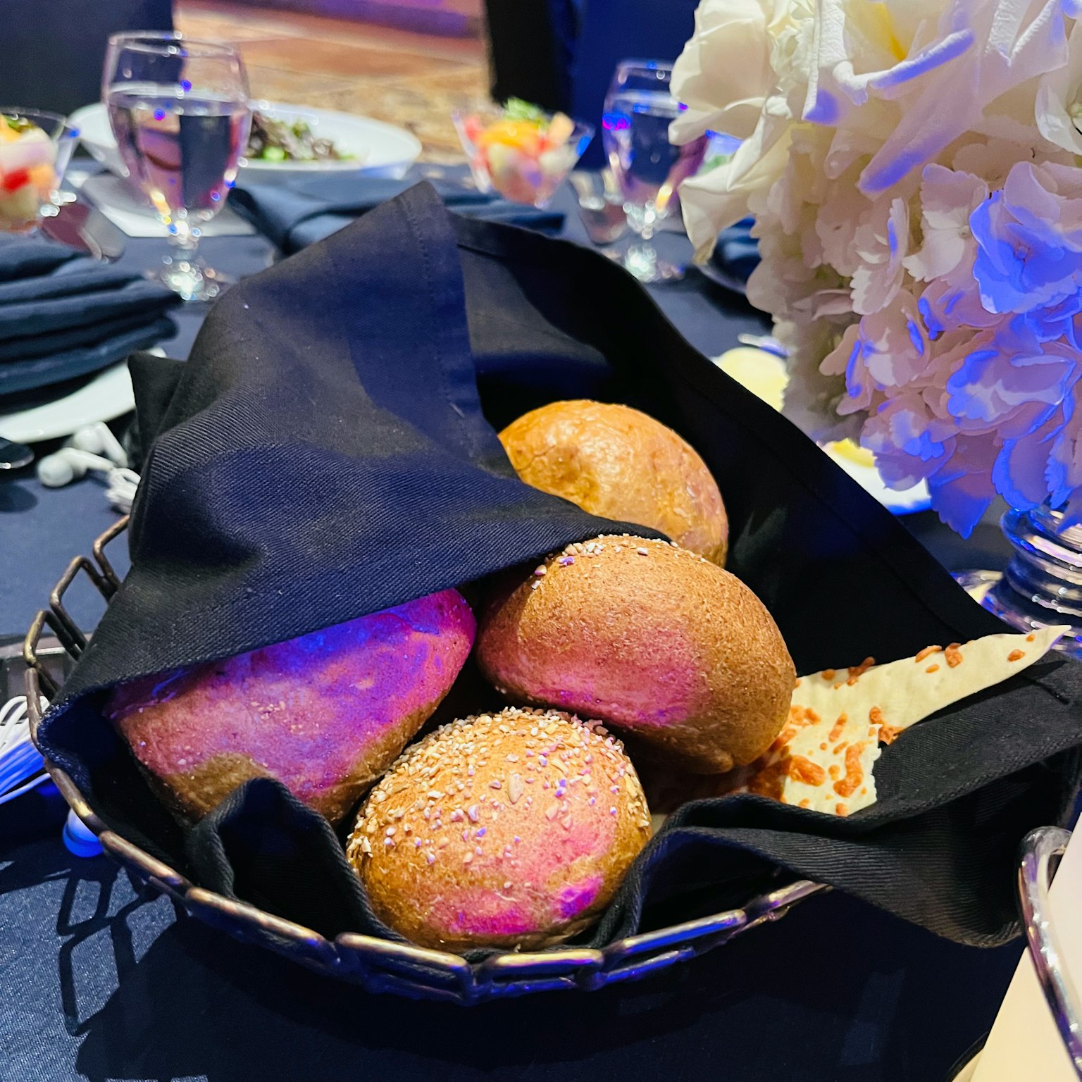 Un panier de petits pains recouvert d'un tissu noir sur une table à manger