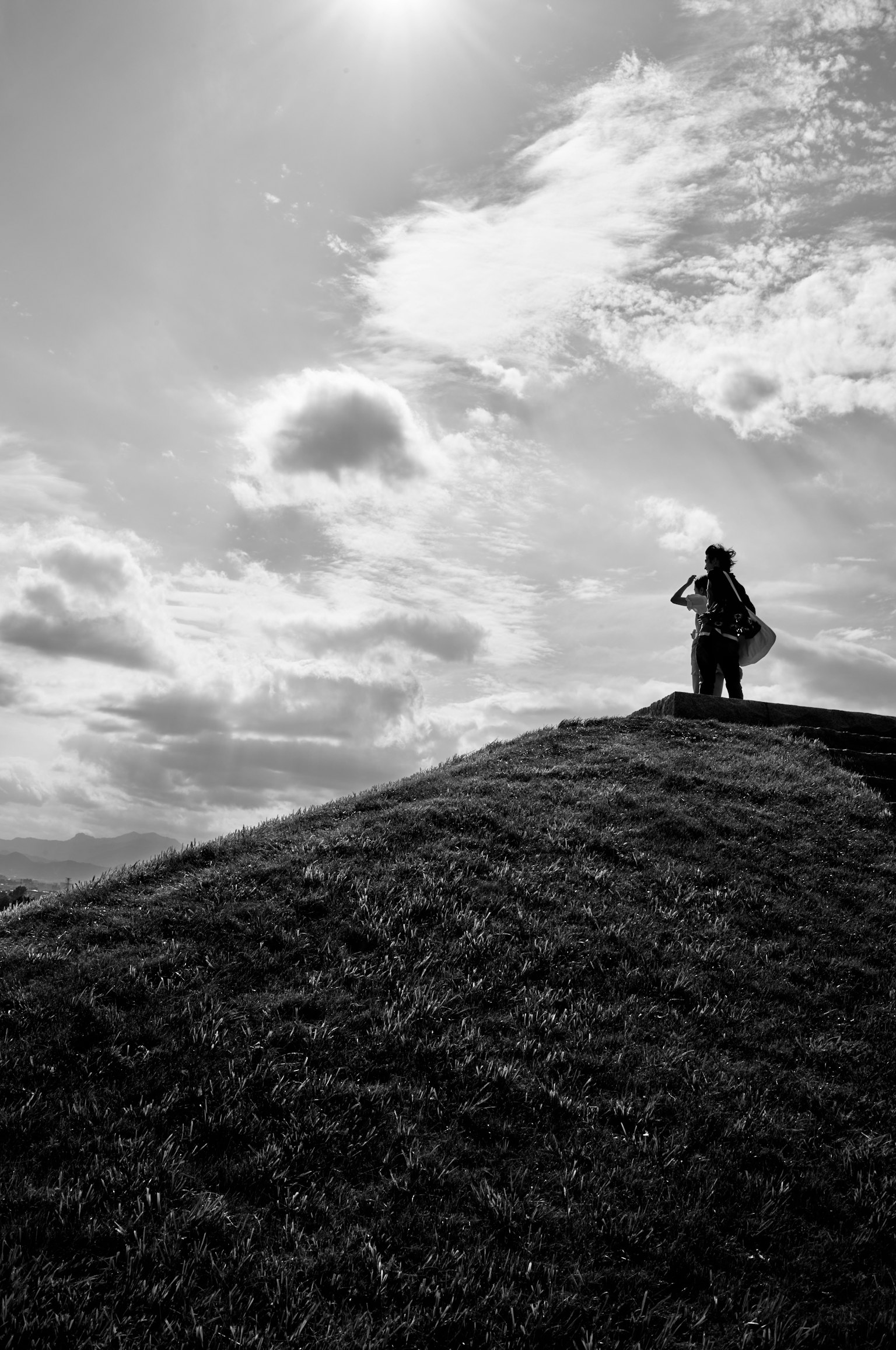 Paysage en noir et blanc avec une personne debout sur une colline nuages et herbe en arrière-plan