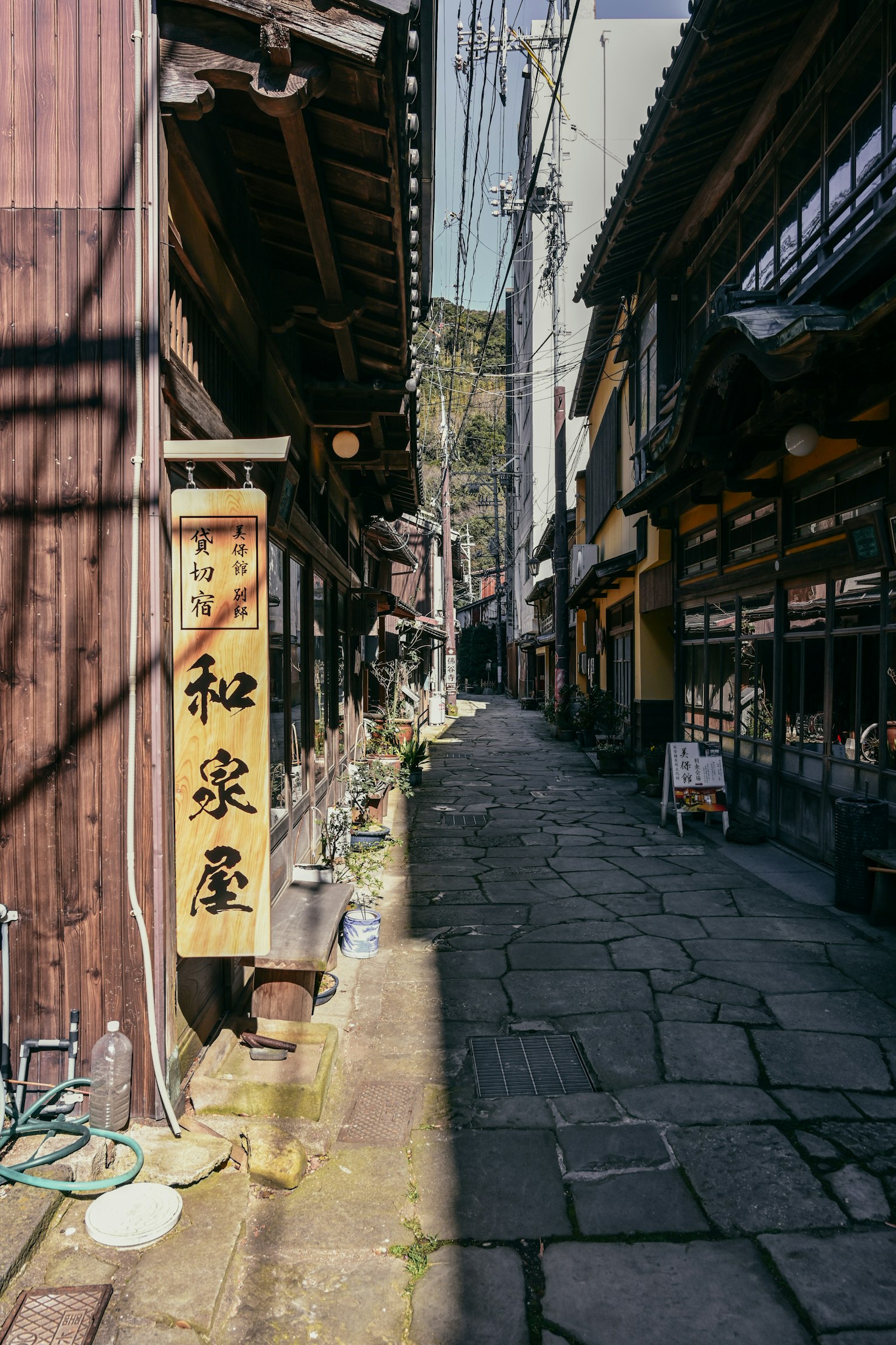 狹窄的石板小巷，兩側是老式木建築，標有'和泉屋'的招牌