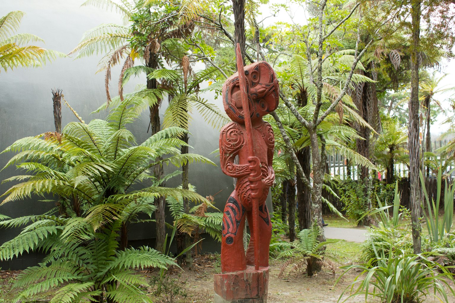 Una escultura de madera roja rodeada de plantas verdes exuberantes en un jardín