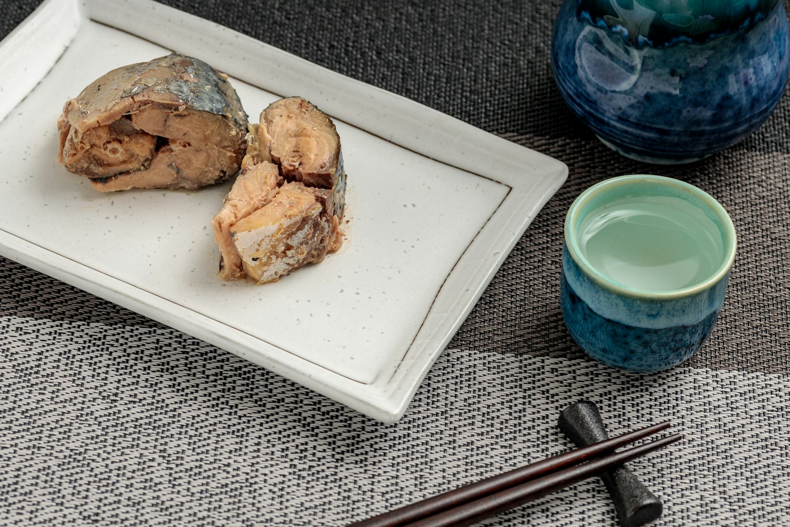 Grilled fish served on a plate with blue ceramic cup