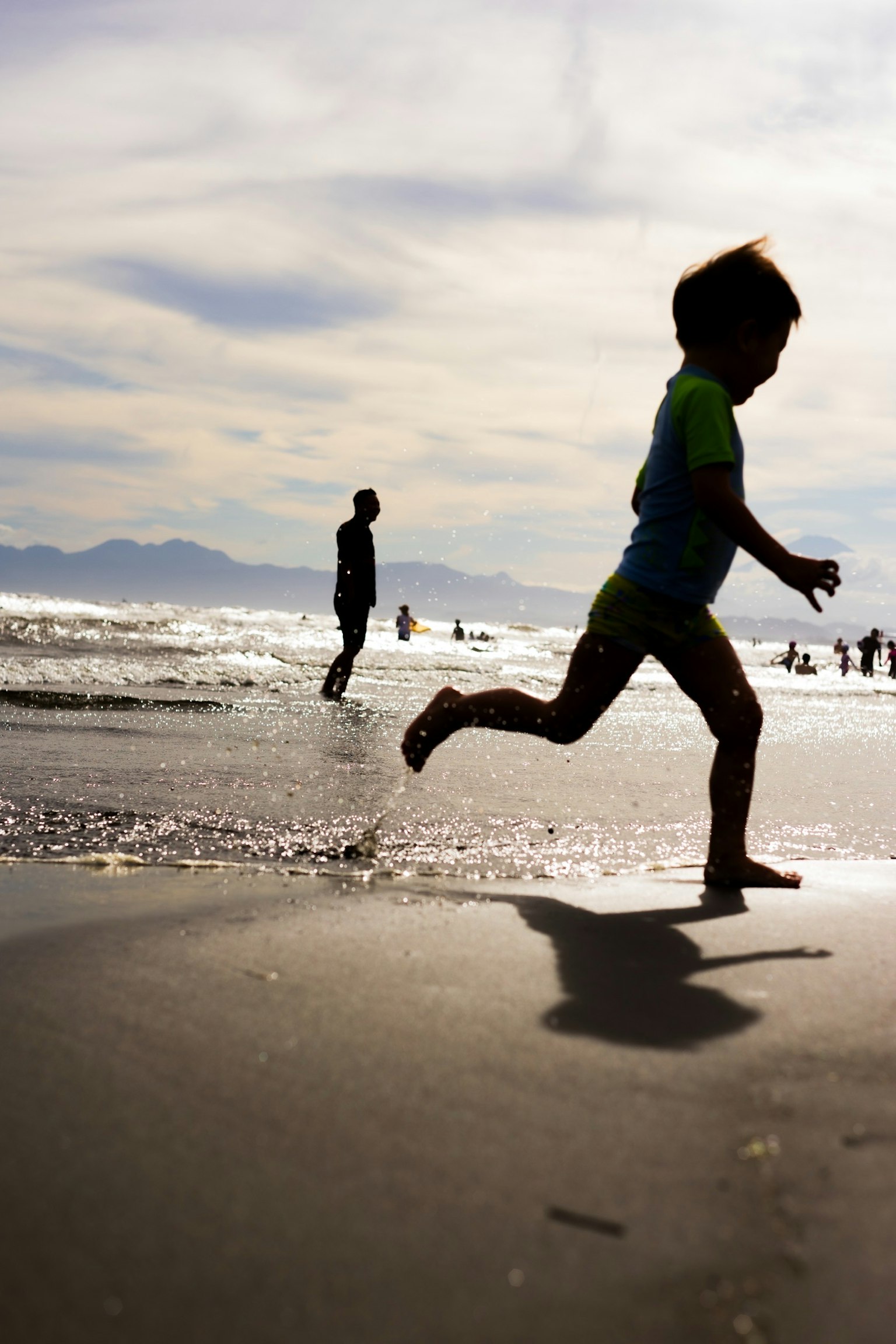 海辺で走る子供のシルエットと波の背景