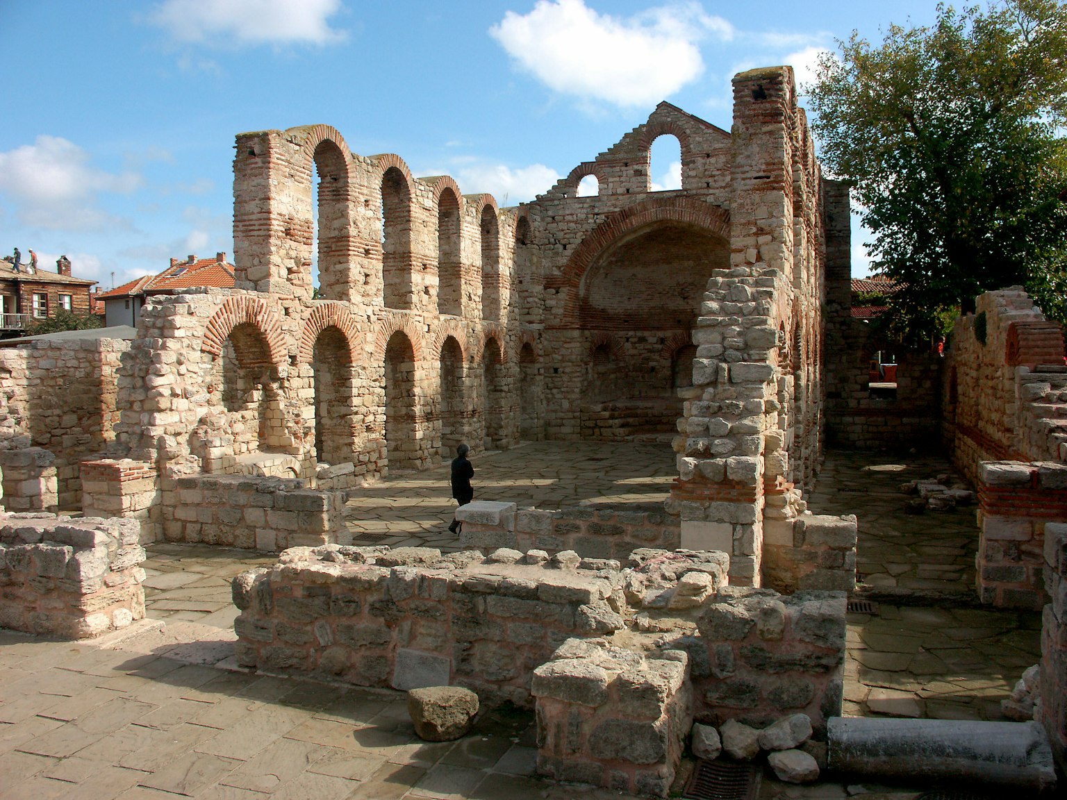Ancient ruins with a person walking under a blue sky