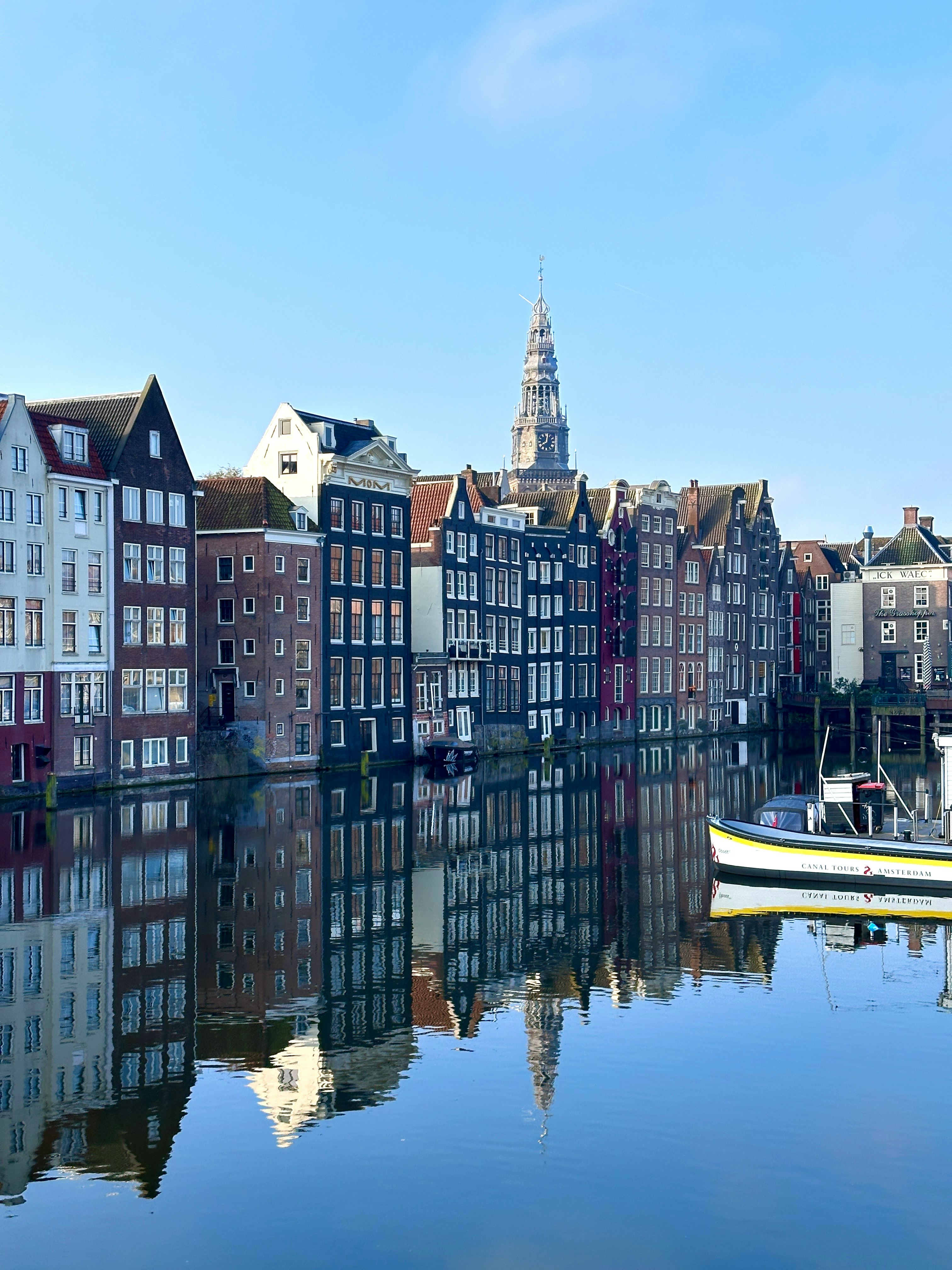 Những ngôi nhà dọc kênh Amsterdam phản chiếu trên mặt nước yên ả kèm thuyền